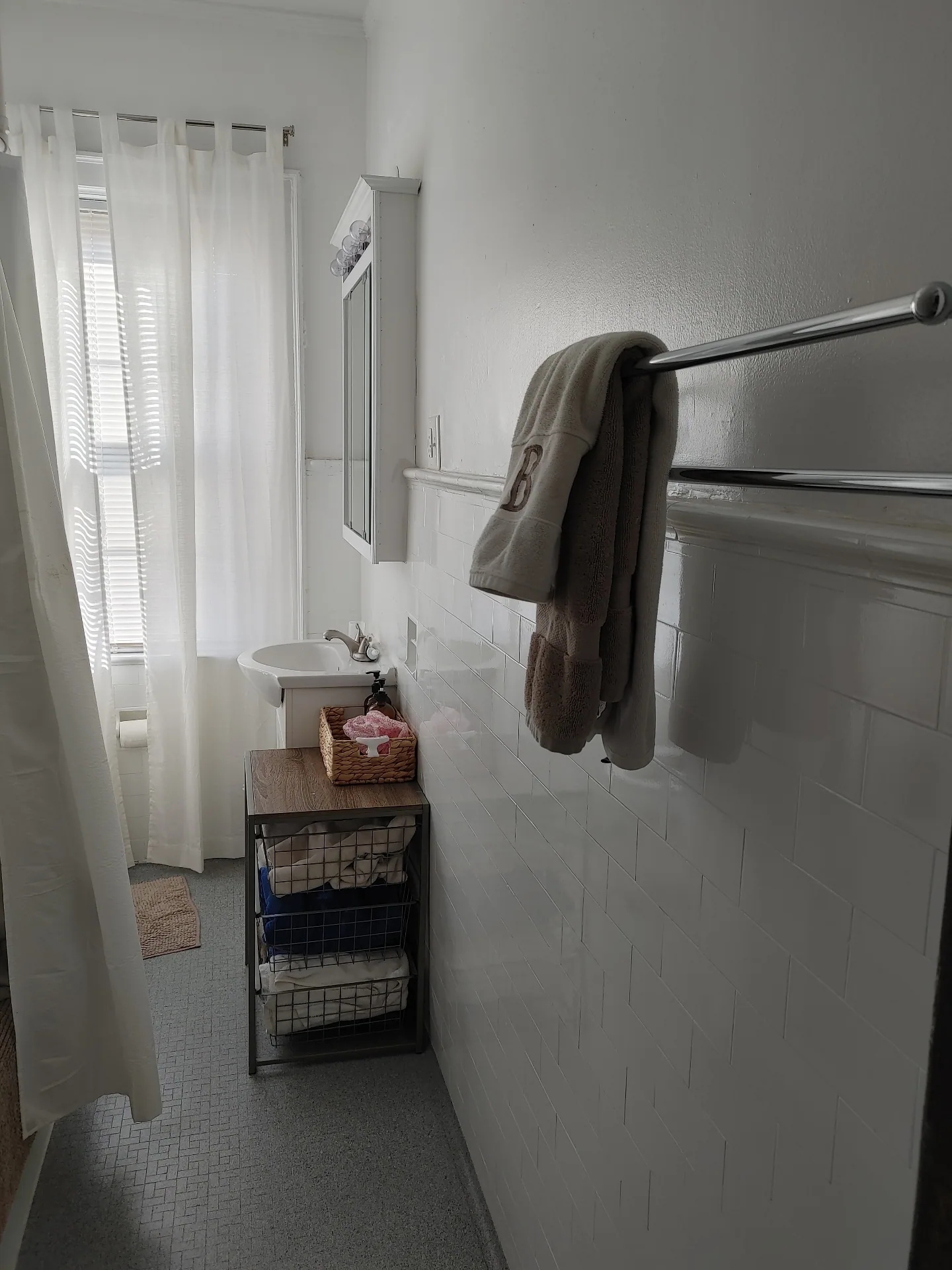 Unit G bathroom with pedestal sink, subway tile wainscoting, and linen storage