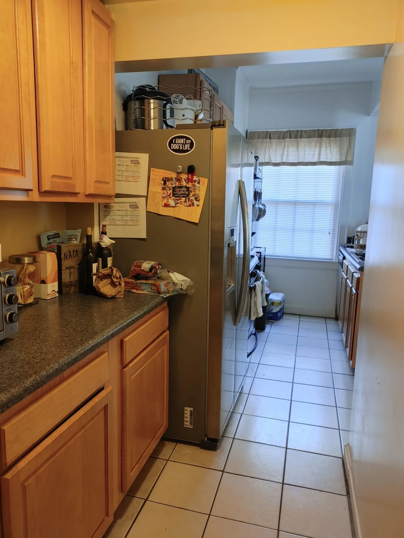 Unit G kitchen with wood cabinets, granite counters, and stainless side-by-side fridge