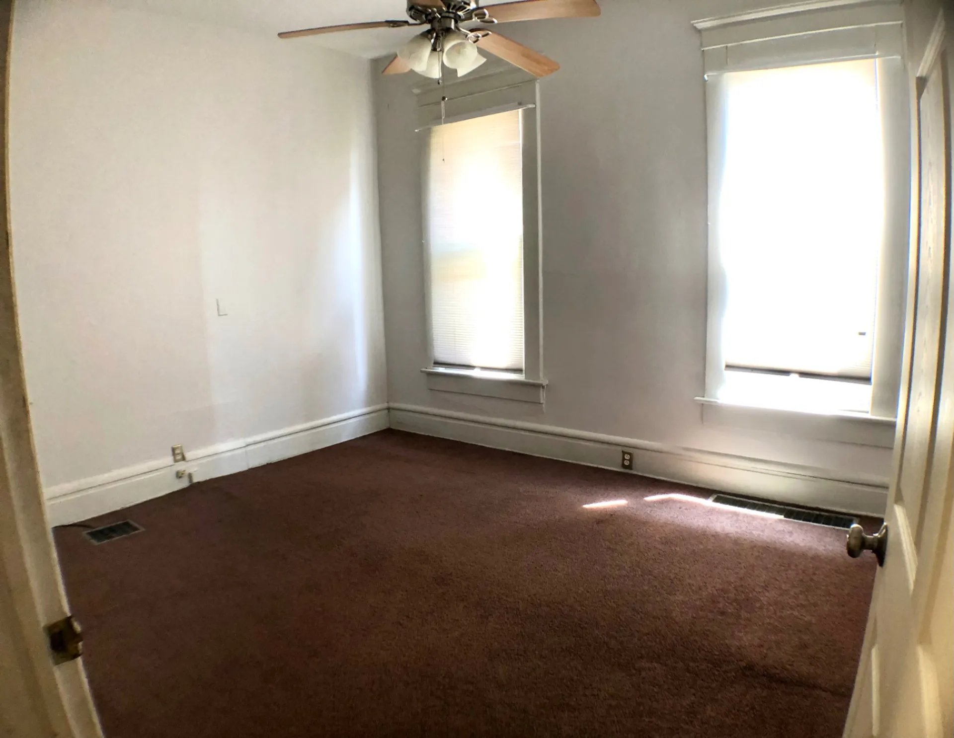 Unit A bedroom with ceiling fan, two bright windows and fresh paint