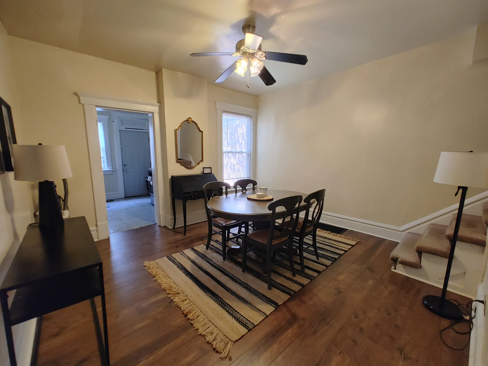 121 W 9th dining room with hardwood floors, ceiling fan, and staircase