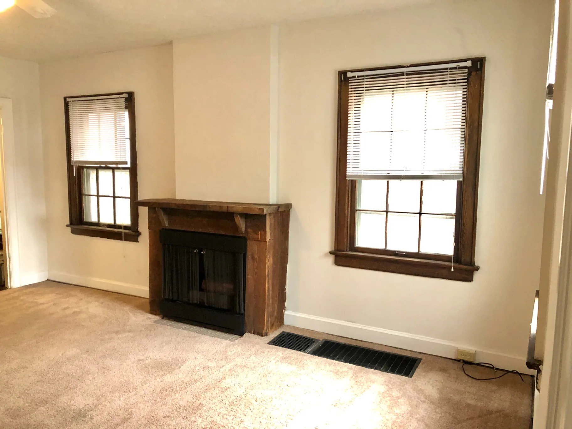 2044 Iuka Ave. B living room with rustic wood-mantel fireplace and bright wood-trim windows