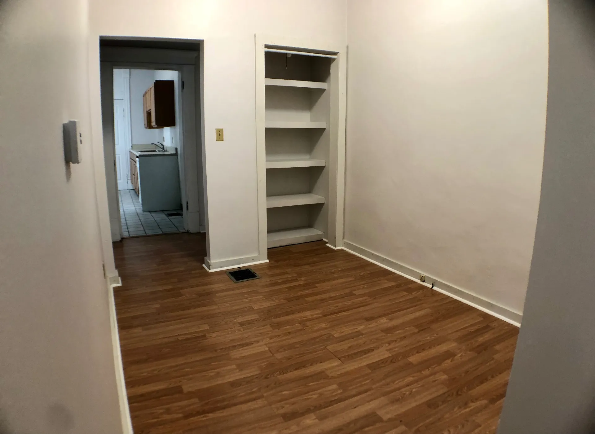 Unit A bedroom with built-in shelving closet and view into the kitchen