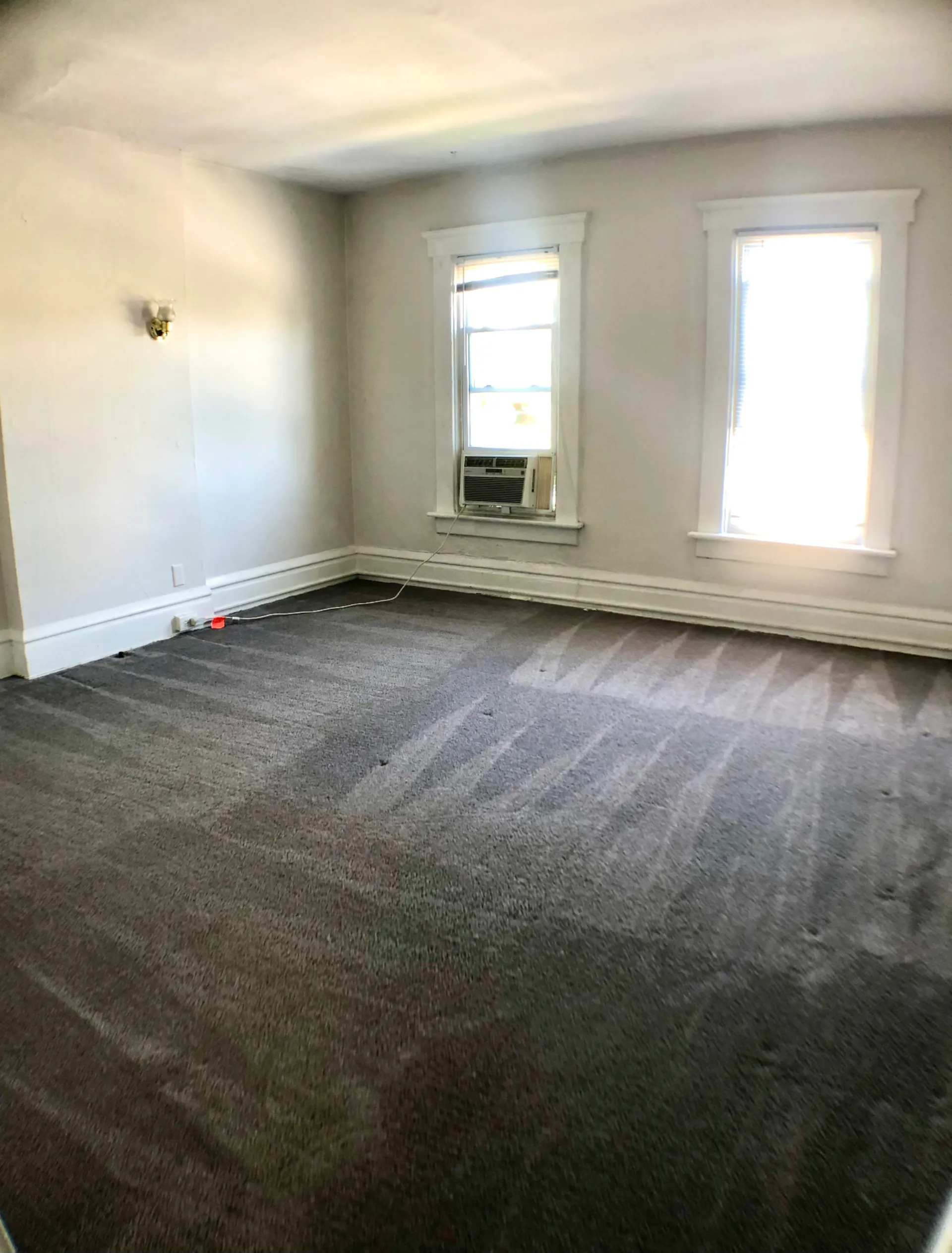 117 W 9th bedroom with grey carpet, wall sconce and dual windows