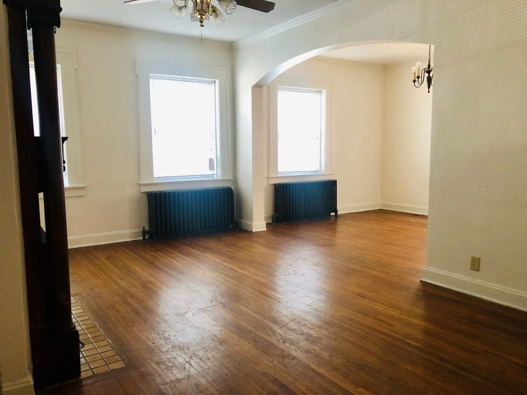 Unit G living and dining rooms with arched entry, tall windows, and chandelier