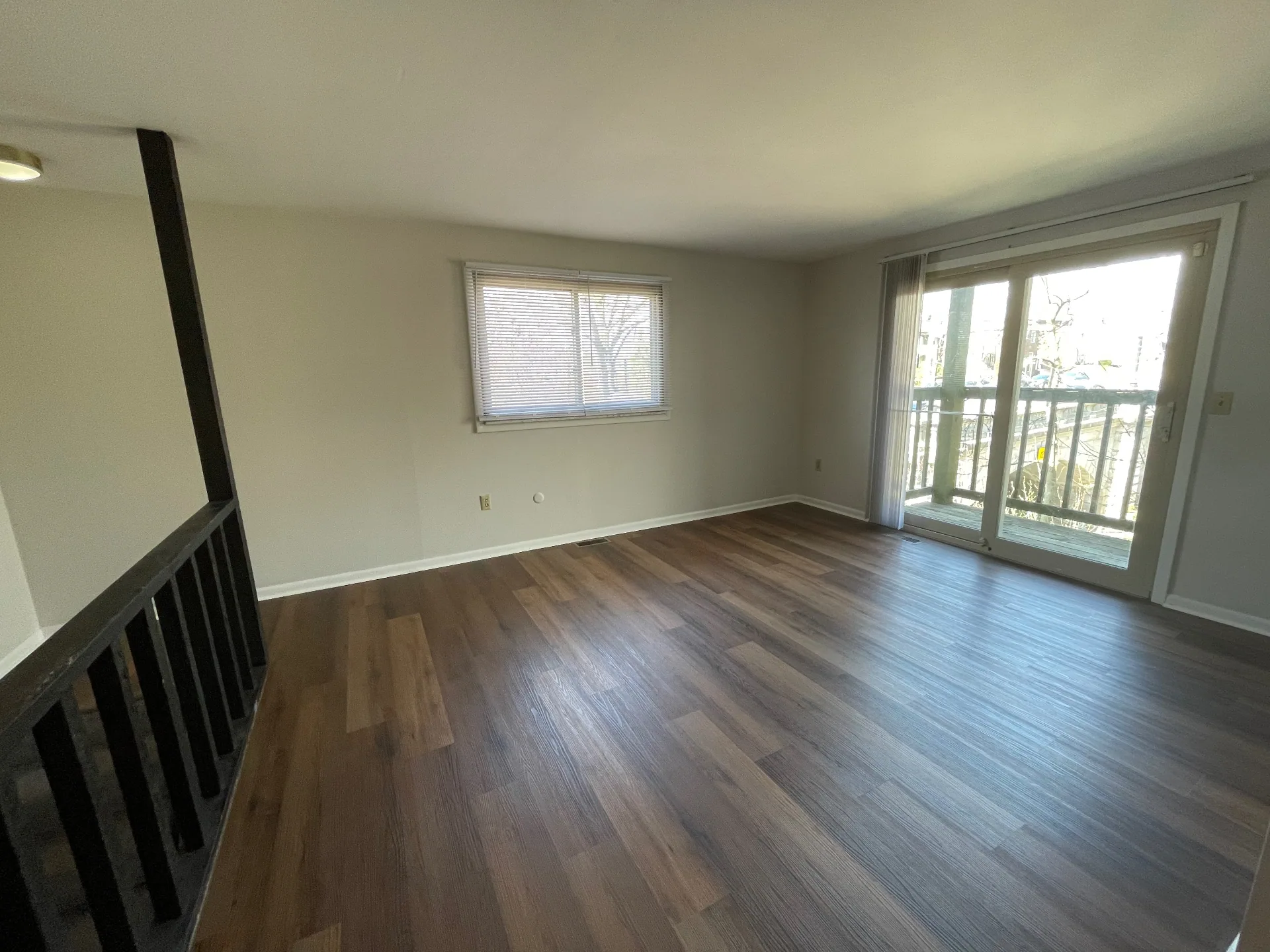 2020 Summit St. open living room with warm plank floors, large window, and sliding glass doors to the private balcony