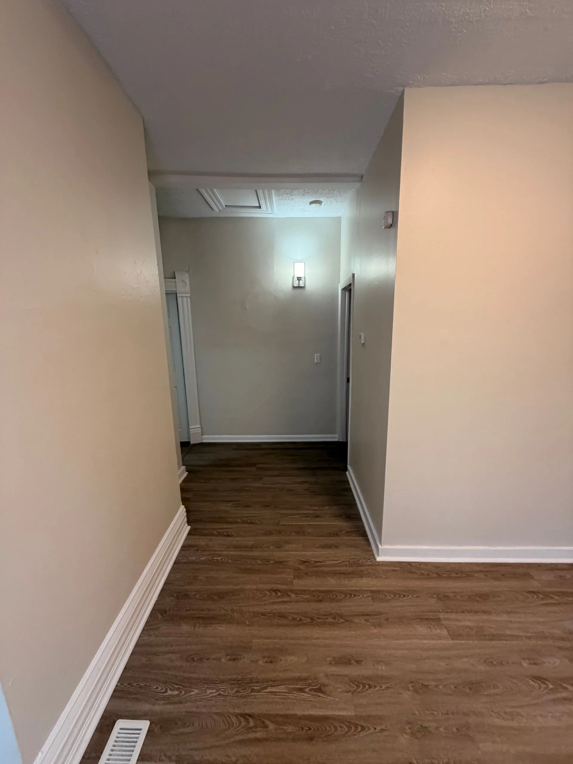 133½ interior hallway with wall sconce and plank flooring