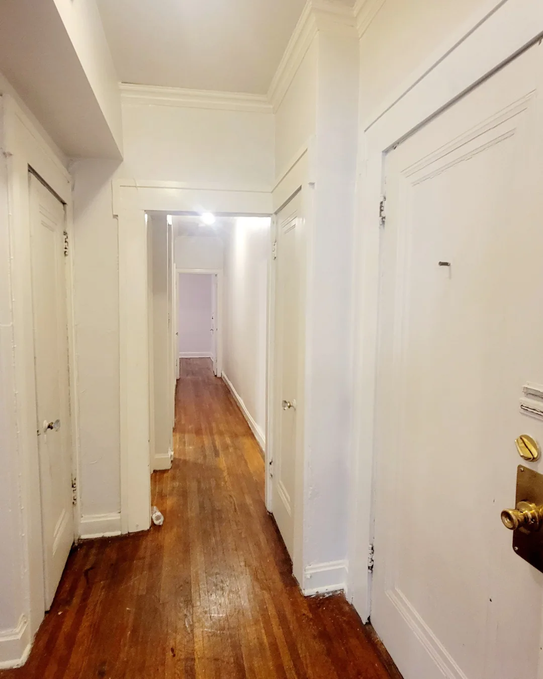 Unit A front hallway with hardwood floors and doors leading to bedrooms and bath
