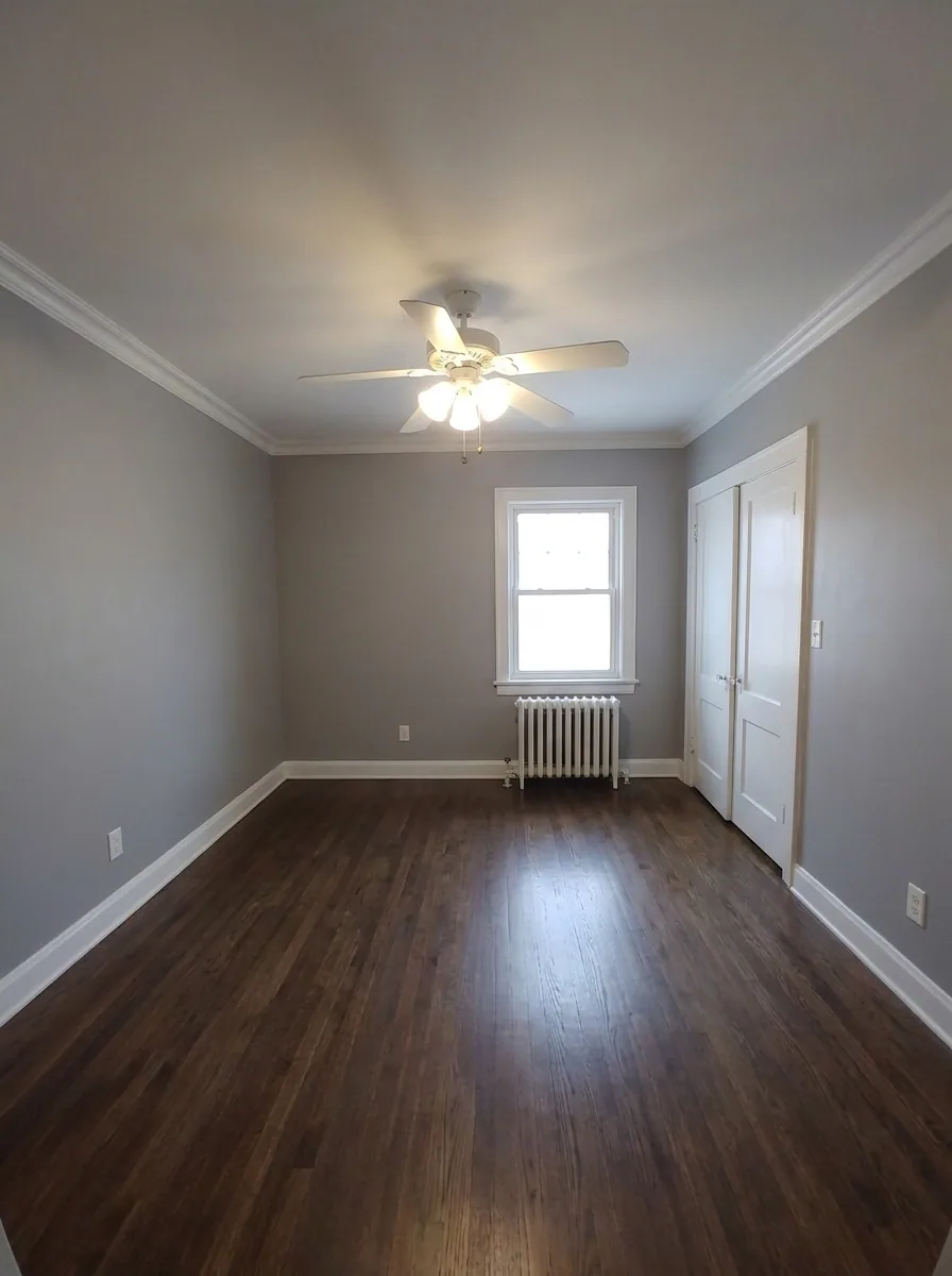 Unit C bedroom with gray walls, hardwood floors, and radiator