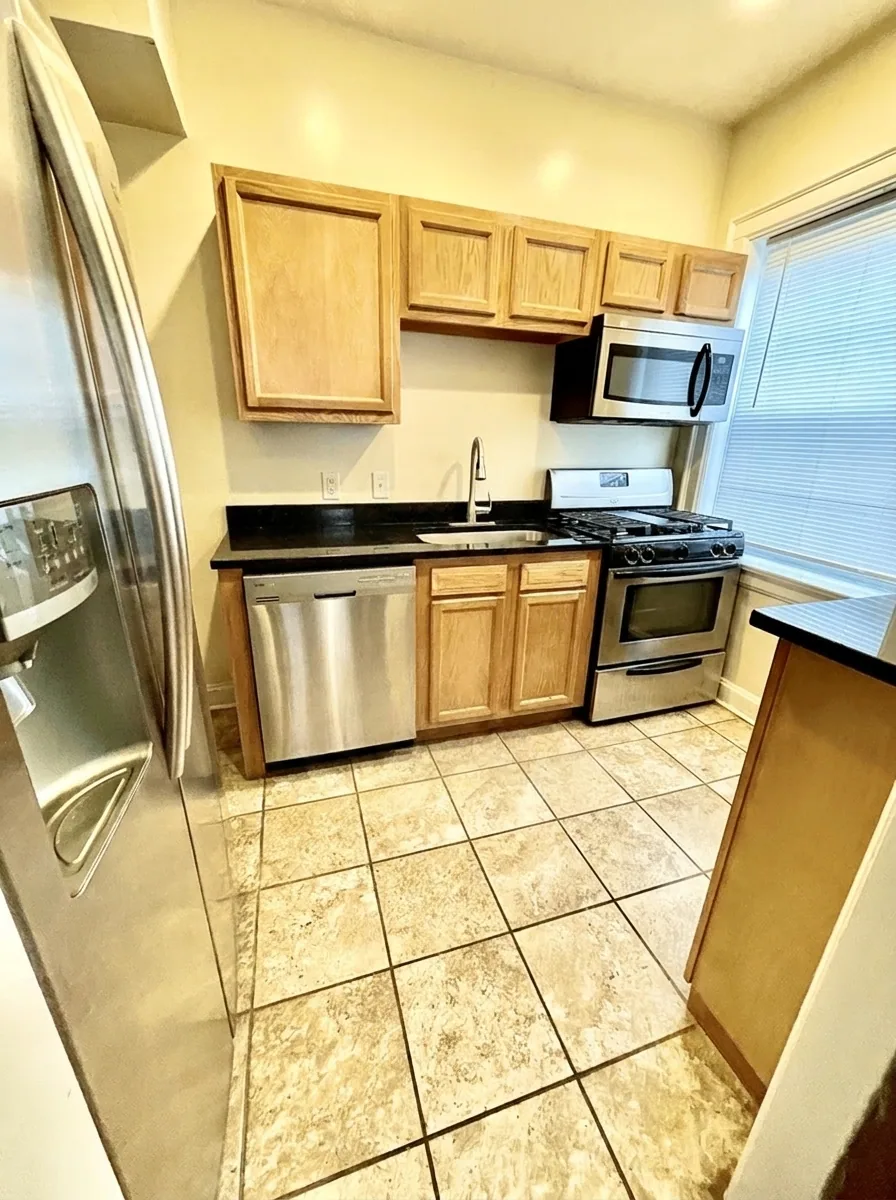 Unit D kitchen with stainless steel appliances and wood cabinets