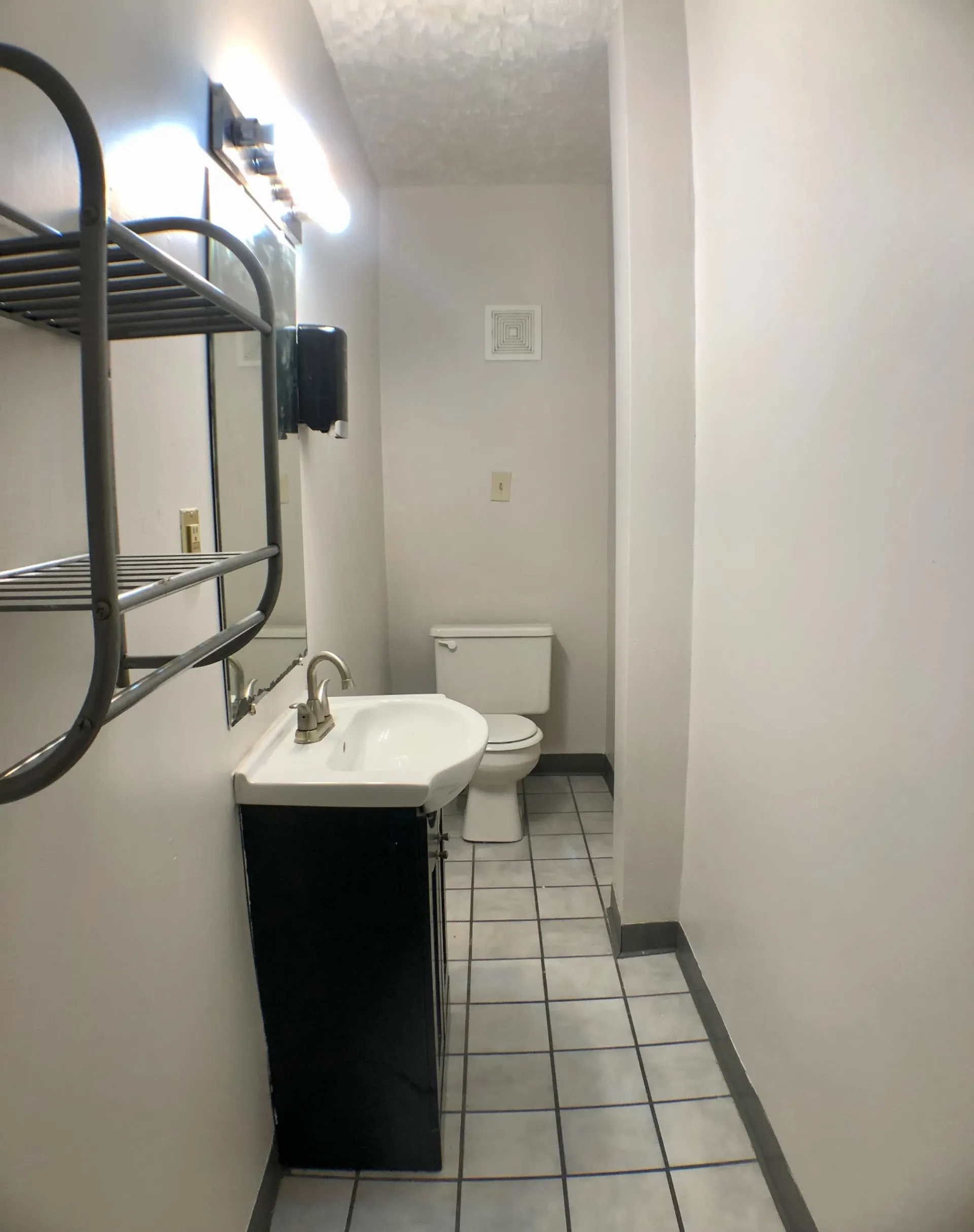 Unit A bathroom with tile floor, black vanity and pedestal-style sink