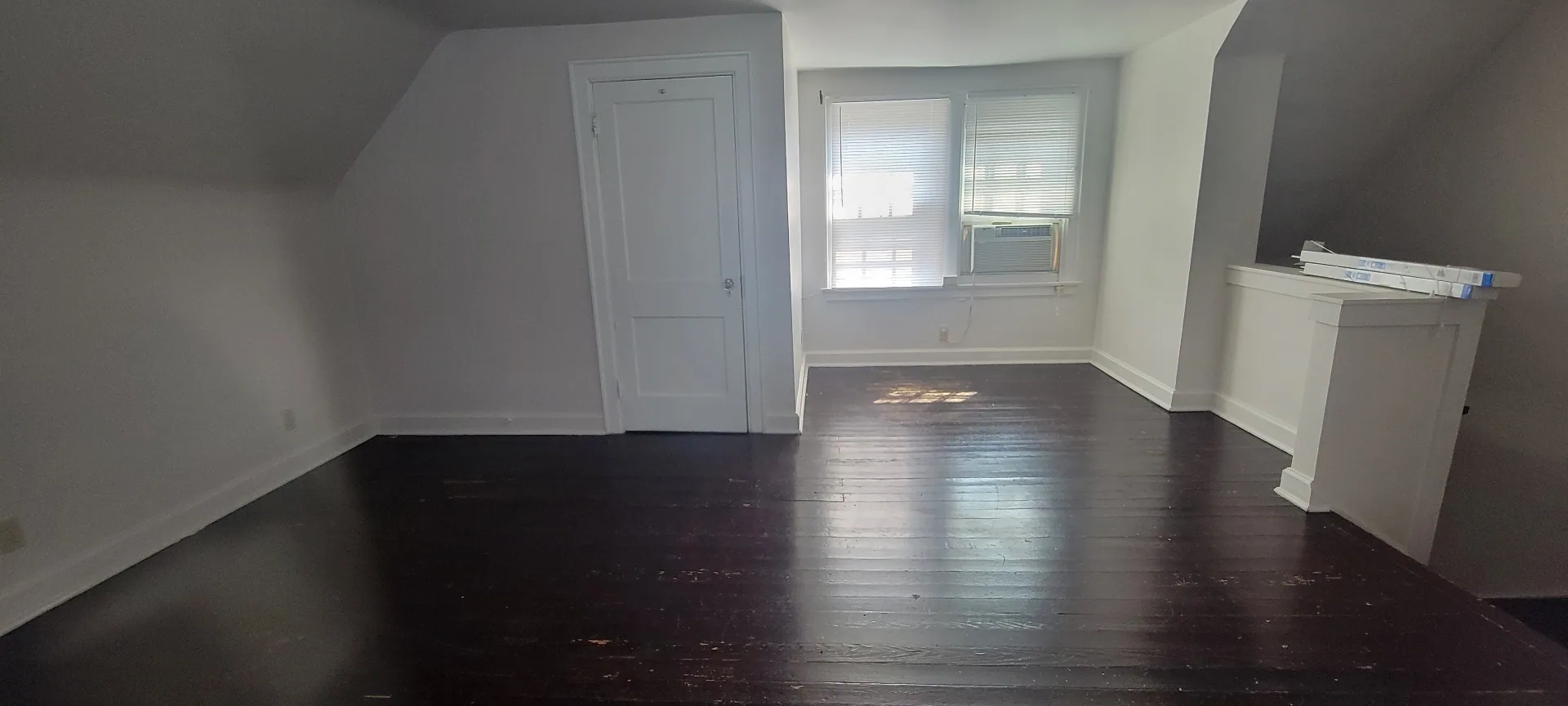 2044 Iuka Ave. C upper-level room with window AC, dark floors, and generous flex space