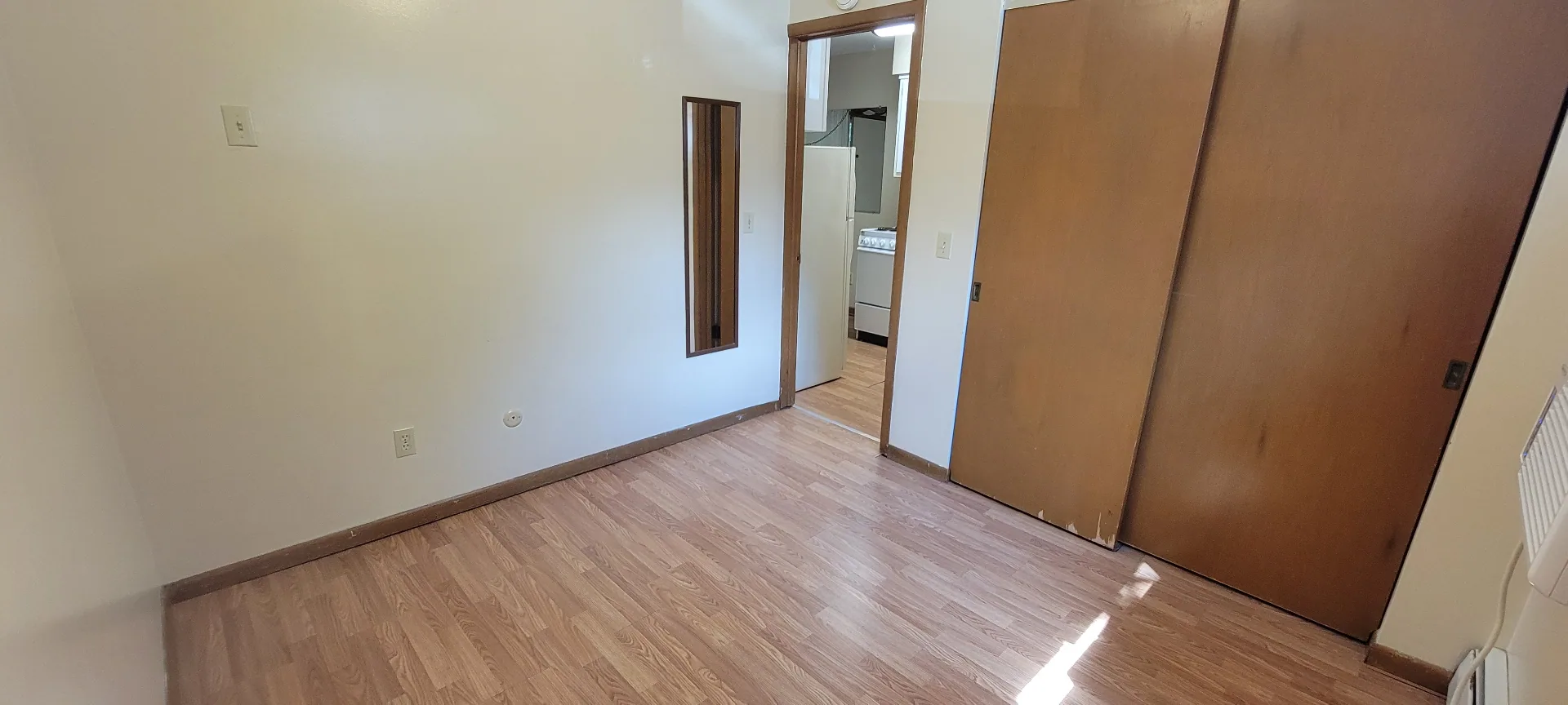 2040 Iuka Ave. 3A bedroom with laminate floors, sliding closet doors, and wall mirror