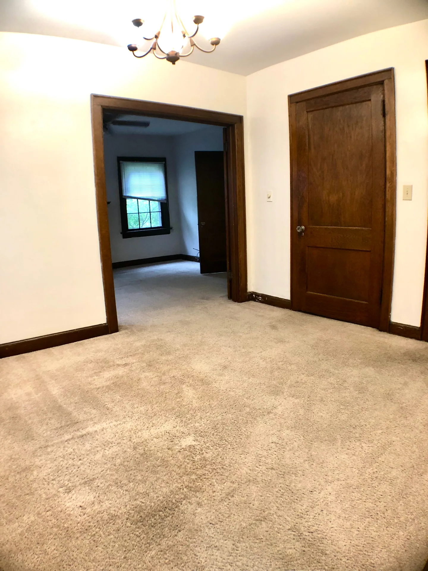 2054 Iuka Ave. D dining/flex room with chandelier, original wood doors, and pass-through to the front room