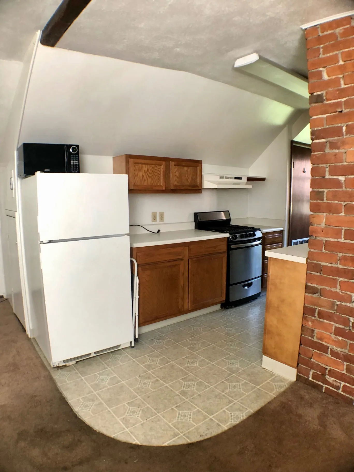 Wide view of galley kitchen with fridge, microwave, and tile floor
