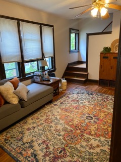 2155 N 4th St. staged living room with hardwood floors, area rug, and stair landing