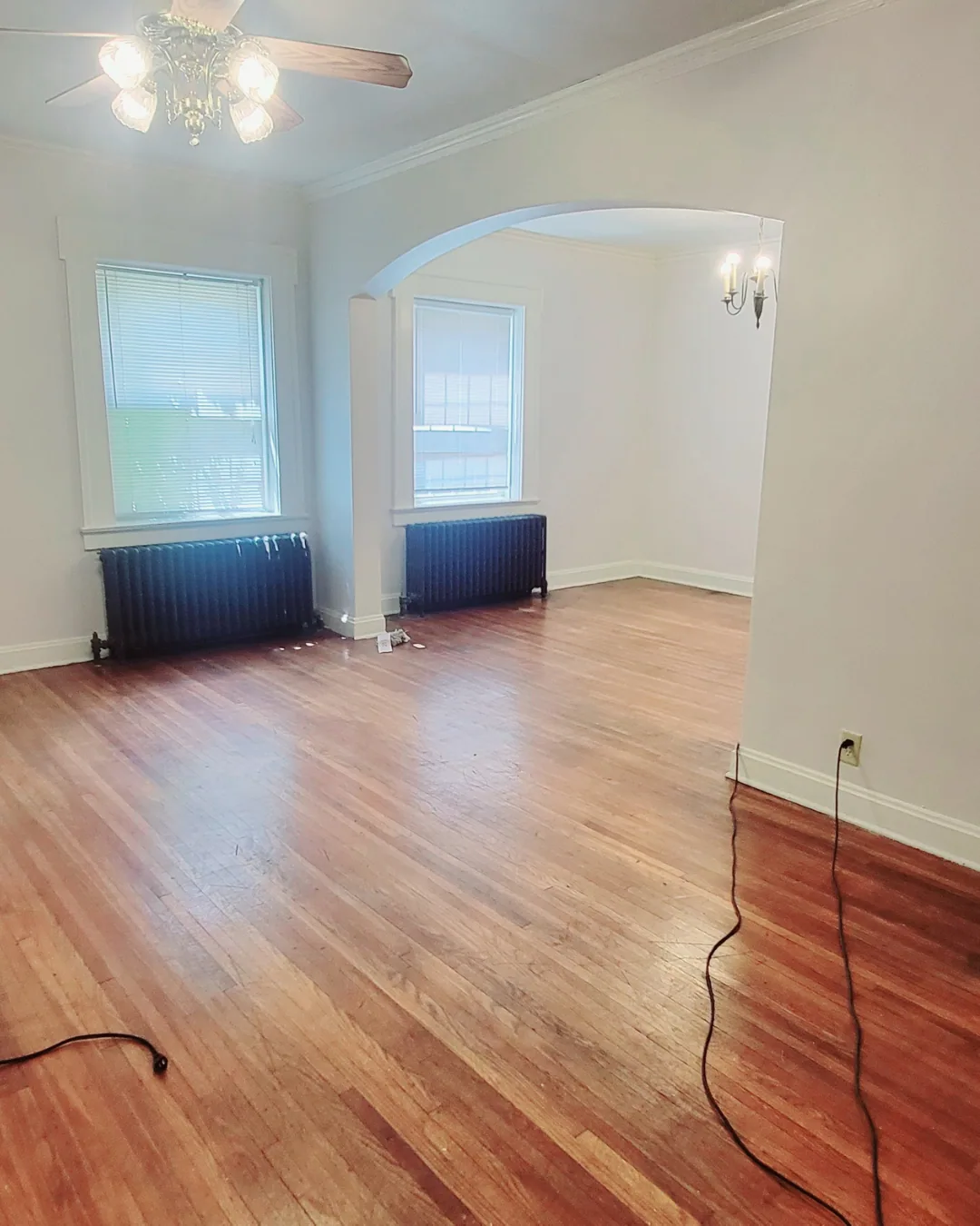 Unit A living room with hardwood floors, ceiling fan, and archway to dining area