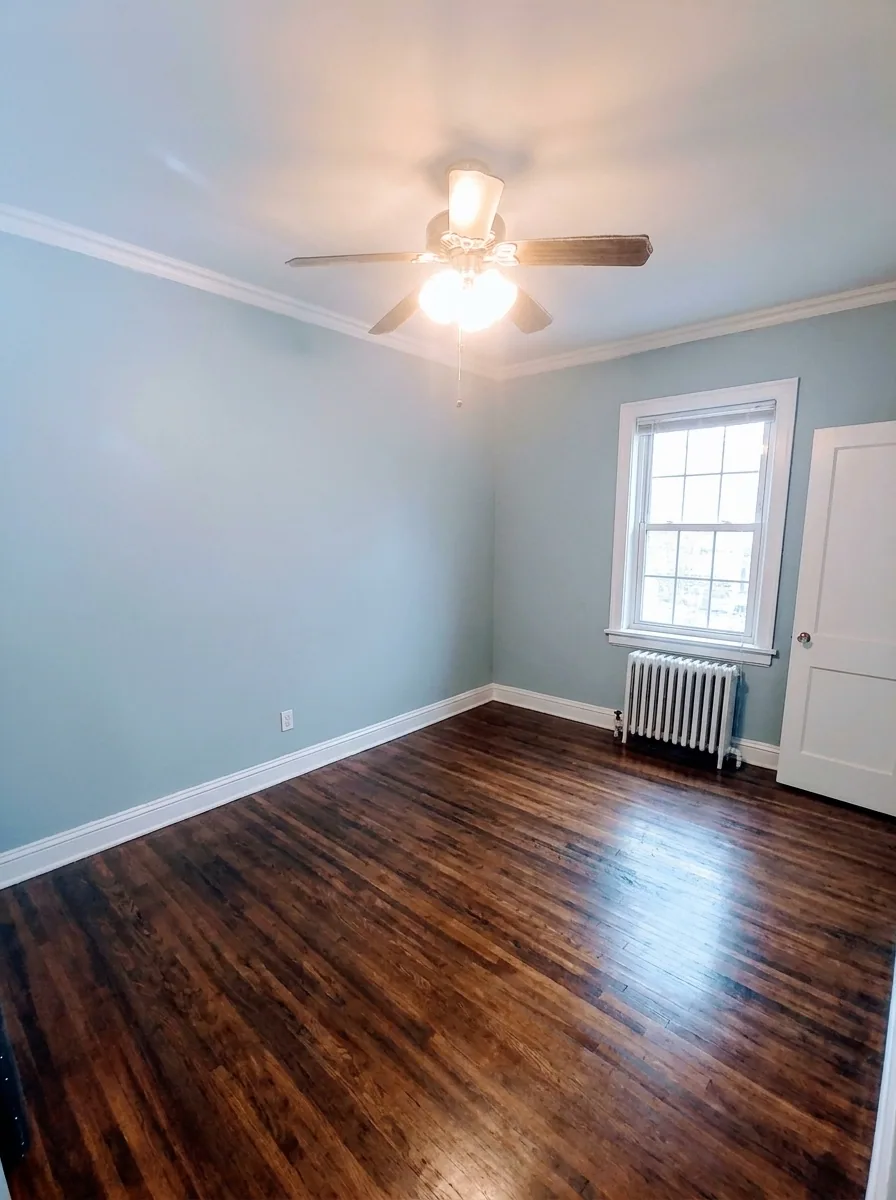 Unit B bedroom with soft blue walls, hardwood floors, and natural light