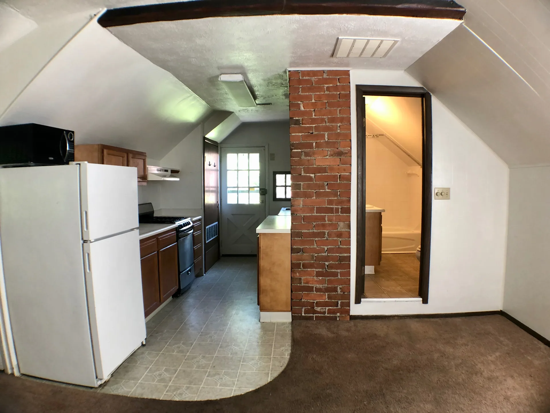 Kitchen looking toward bathroom entry and exposed brick divider