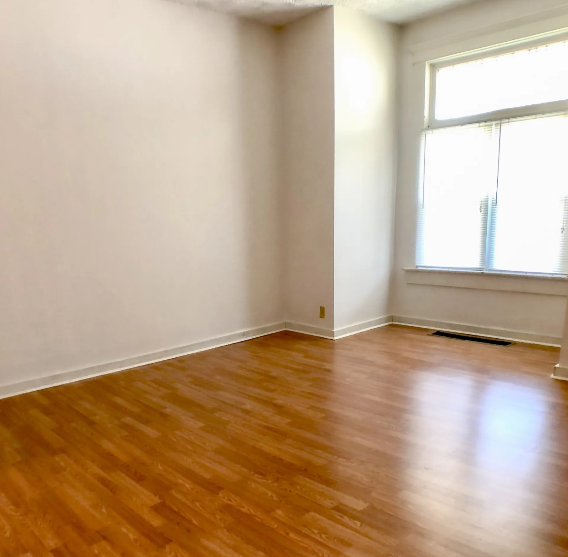 Unit A bedroom with hardwood floors and bright corner window