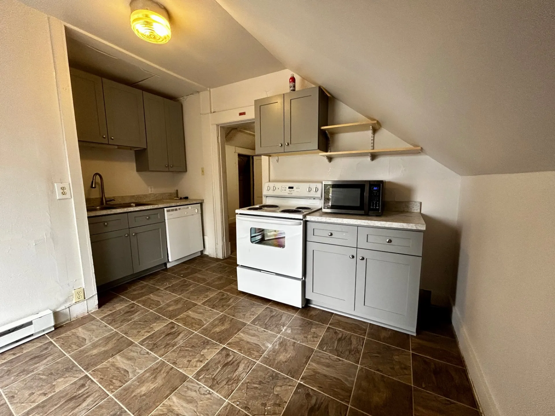 1820 Summit St. updated kitchen with gray shaker cabinets, white range, dishwasher, microwave, and tile floor