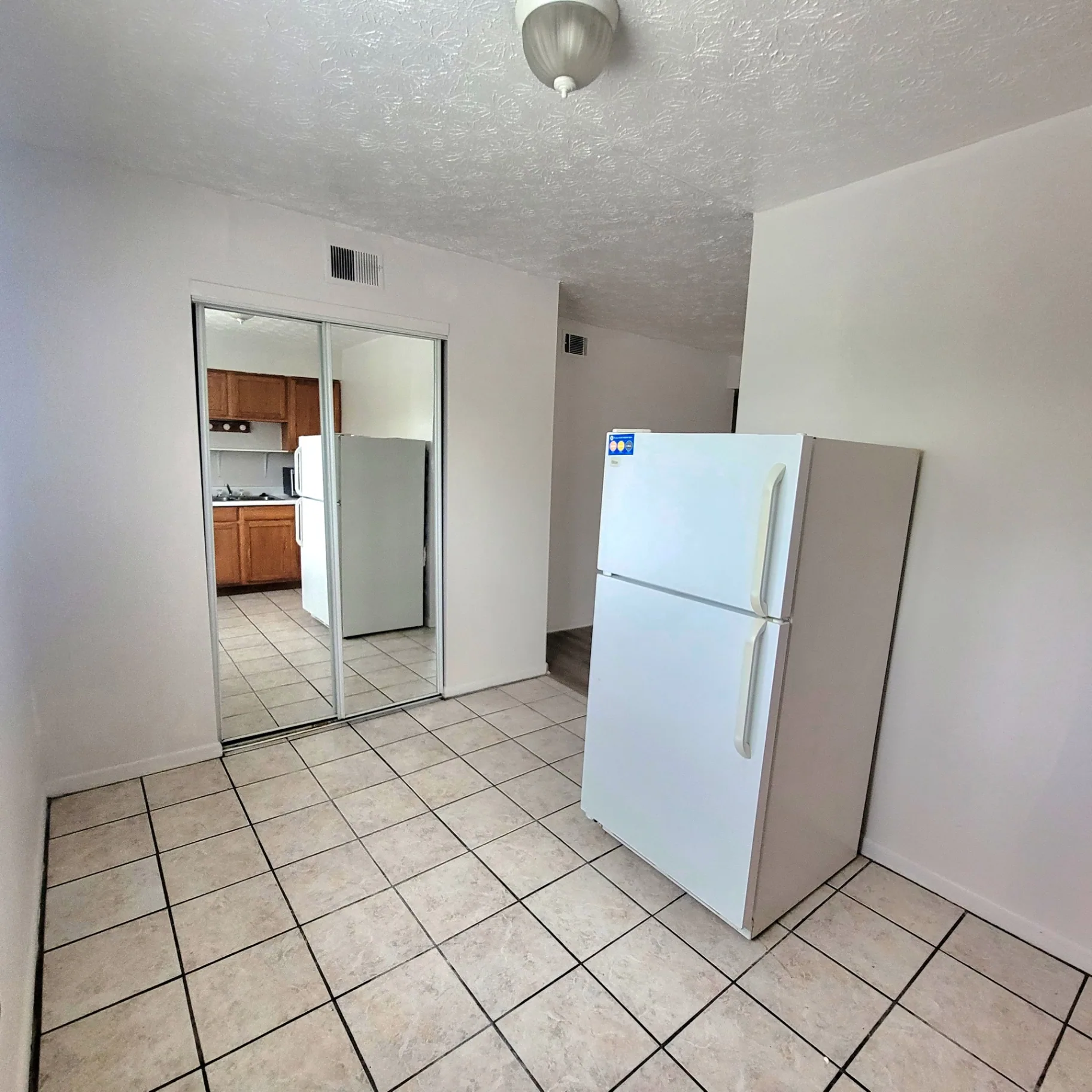 2150 N 4th St. Unit E tiled dining area with white fridge and mirrored closet