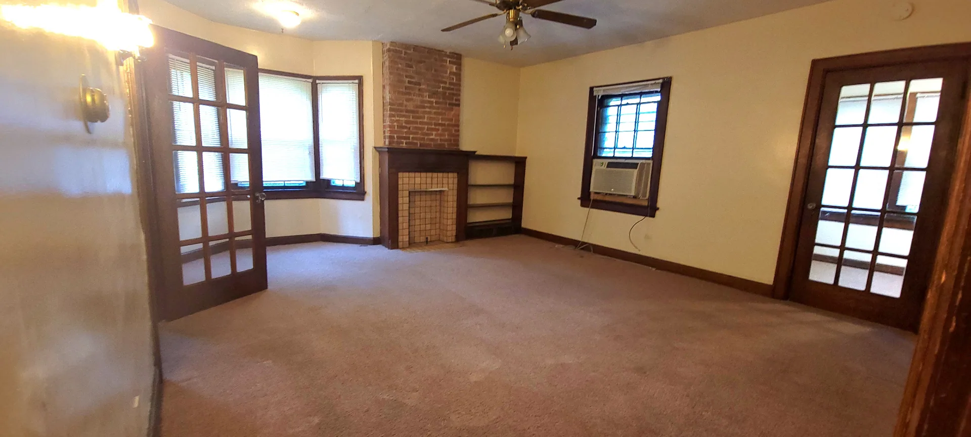 2054 Iuka Ave. C spacious living room with tile fireplace, French doors, bay window, and ceiling fan