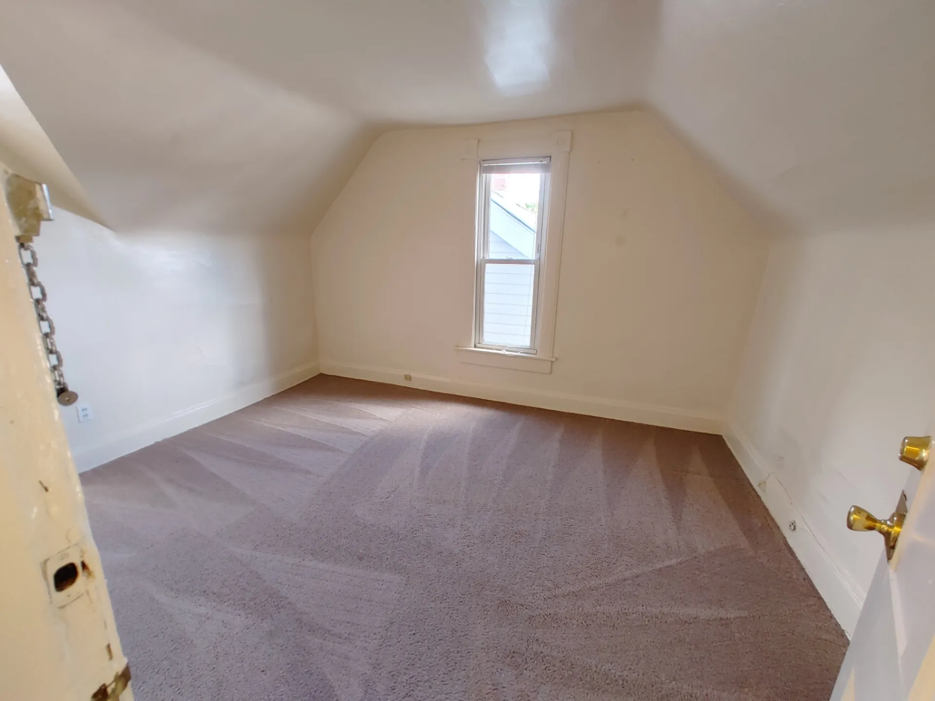 Rear unit upstairs bedroom with vaulted ceiling and tall window
