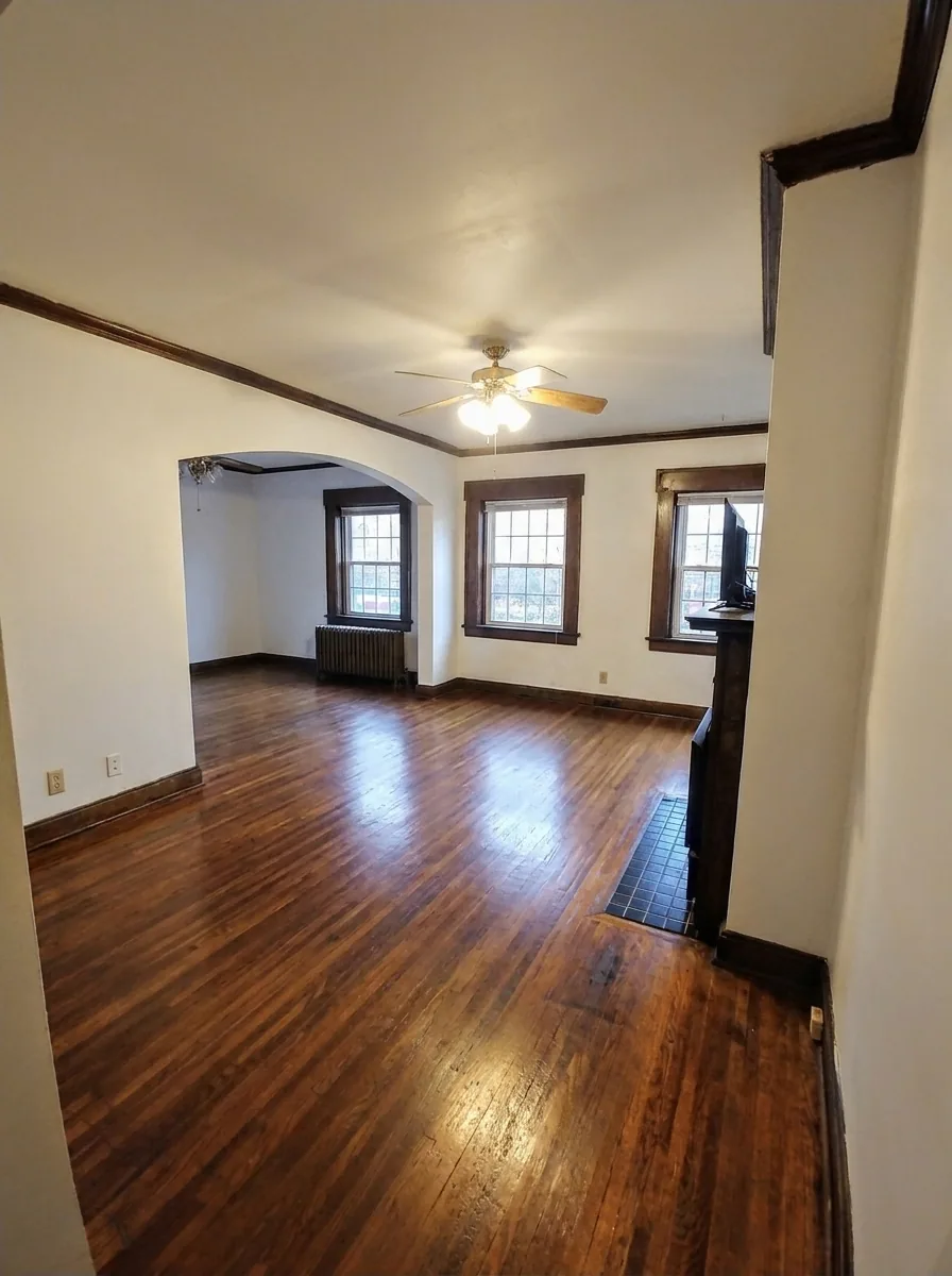 Unit B living and dining area with hardwood floors, archway, and multiple windows