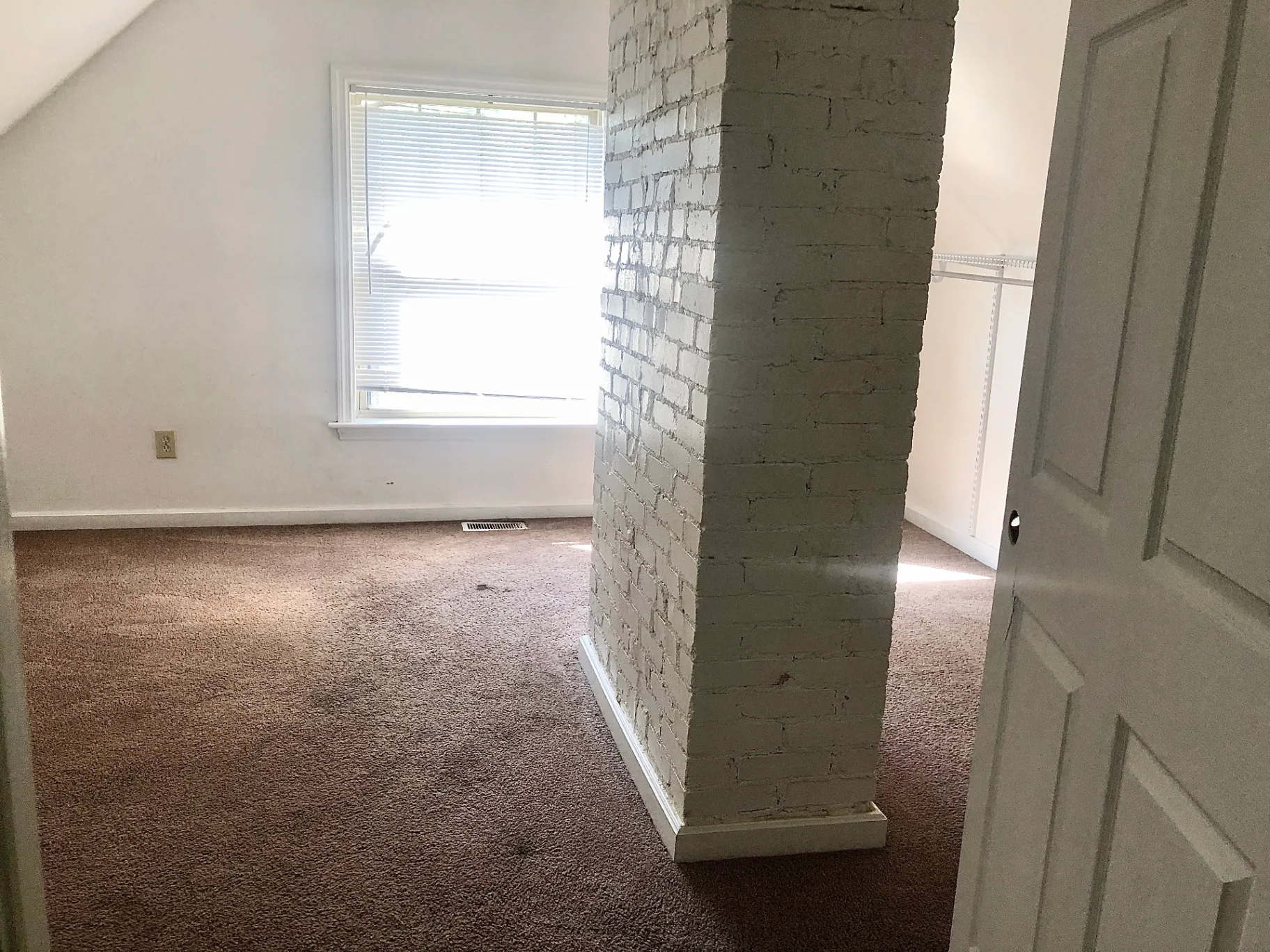 2034 Iuka Ave A upstairs bedroom with exposed painted brick chimney and closet