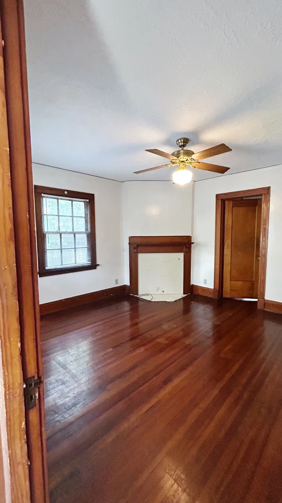 2026 Iuka Ave C bedroom with wood mantel fireplace, glossy hardwood floors, and ceiling fan