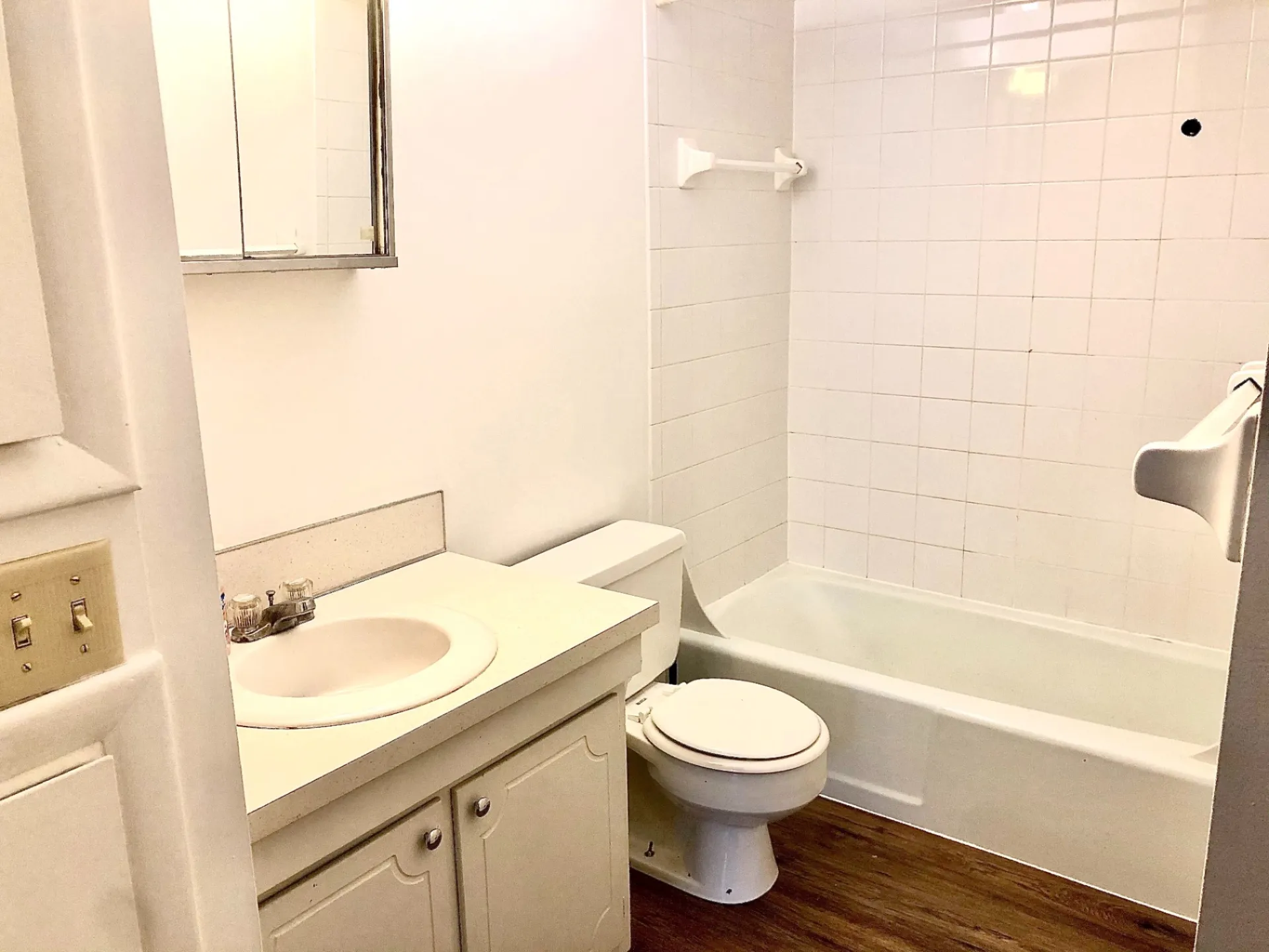2011 Summit St. Unit F bathroom with tub/shower, white tile surround, and wood-look plank flooring