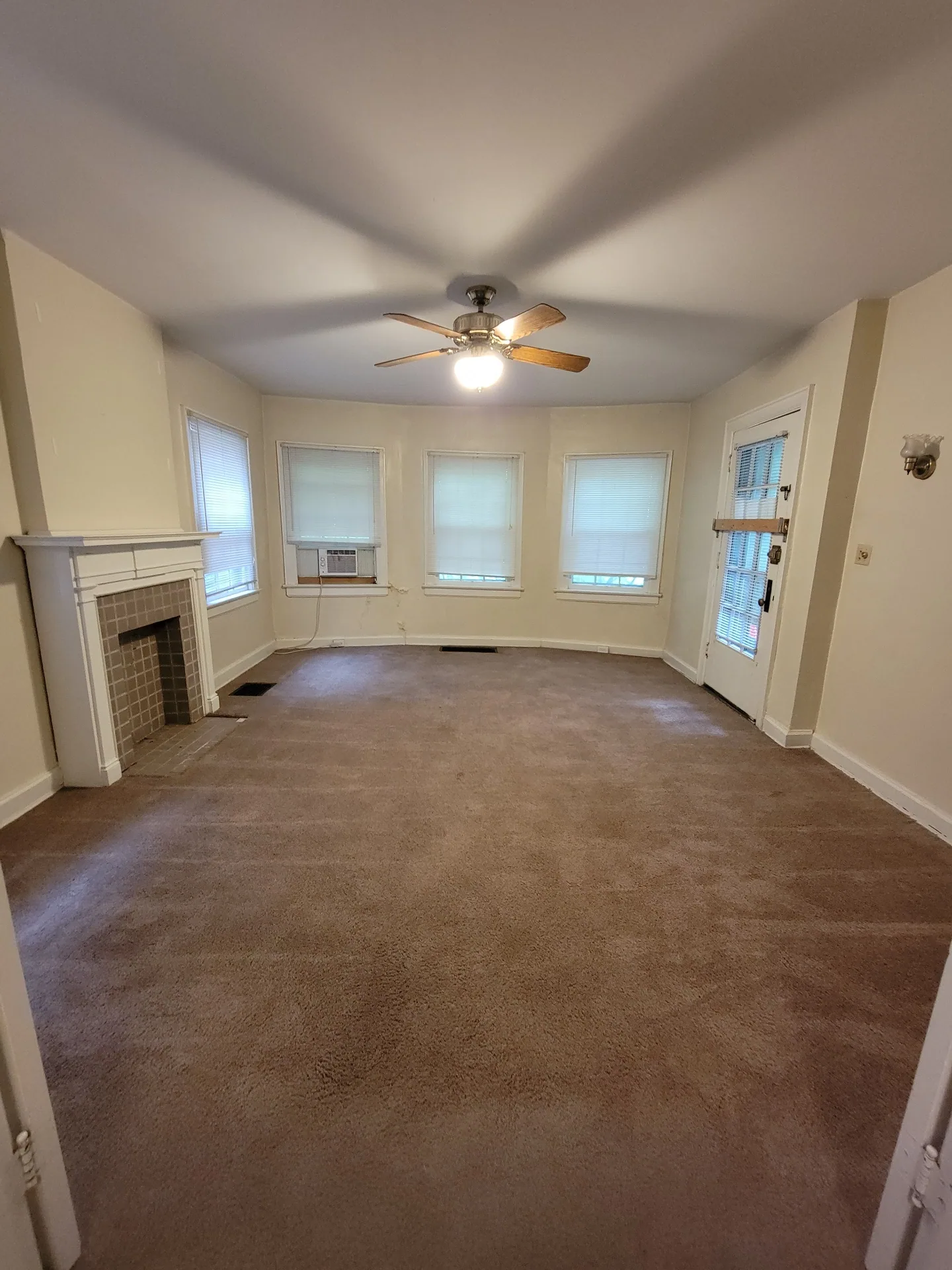 2048 Iuka Ave. B living room angle showing tile fireplace and rear entry door