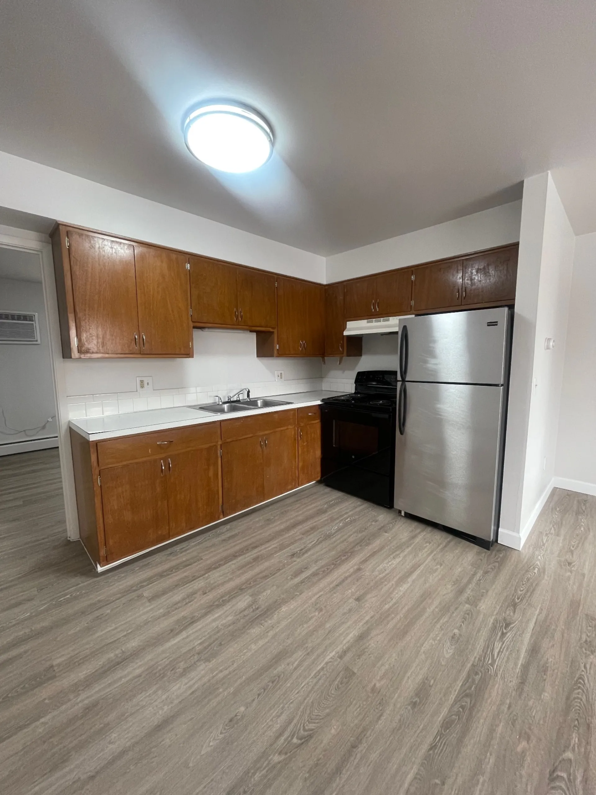 1827 N 4th St. Unit 8 kitchen with maple cabinets, stainless fridge, black electric range, and tile backsplash