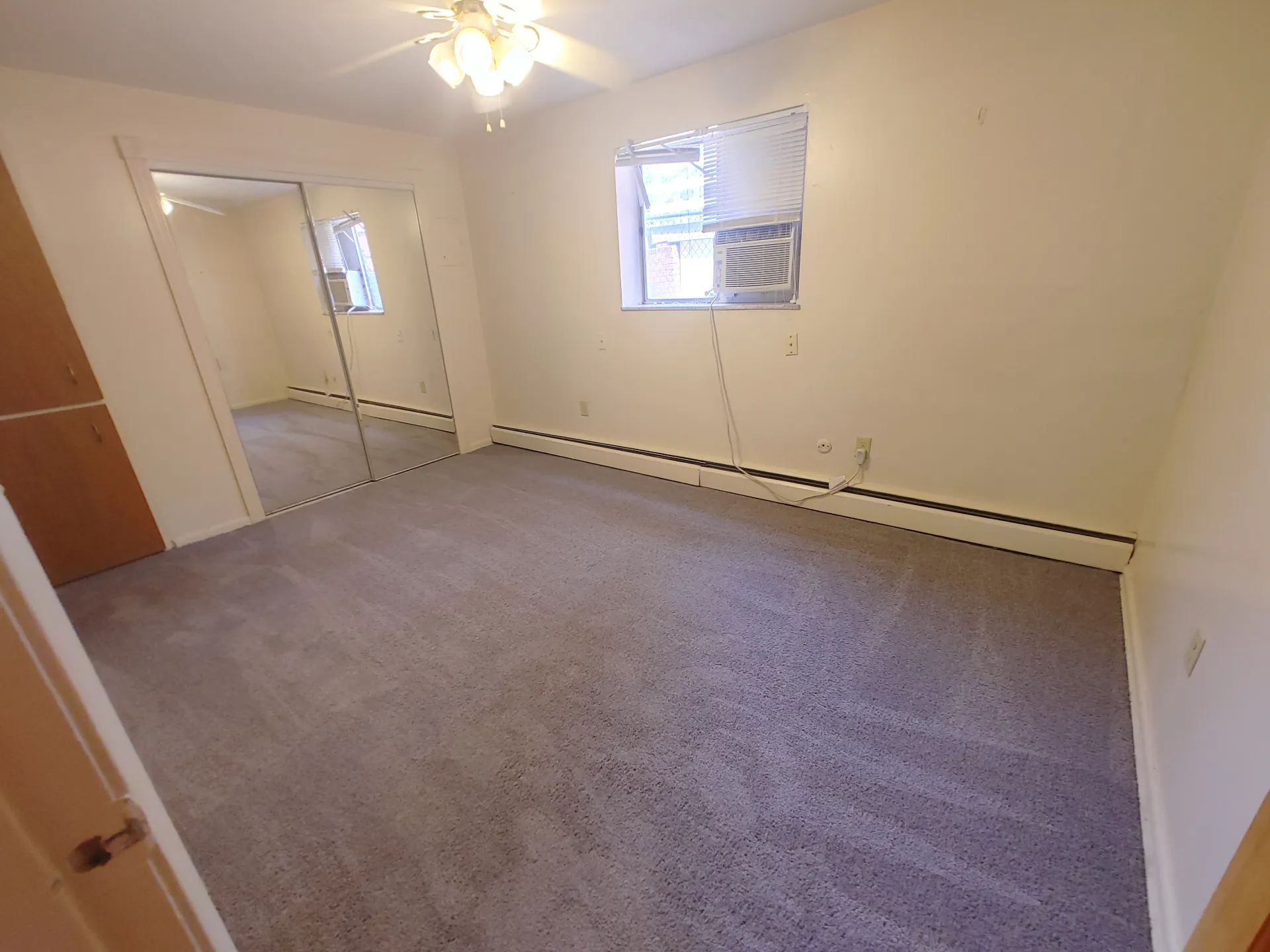 1827 N 4th St. Unit 3 carpeted bedroom with mirrored closet doors and window AC
