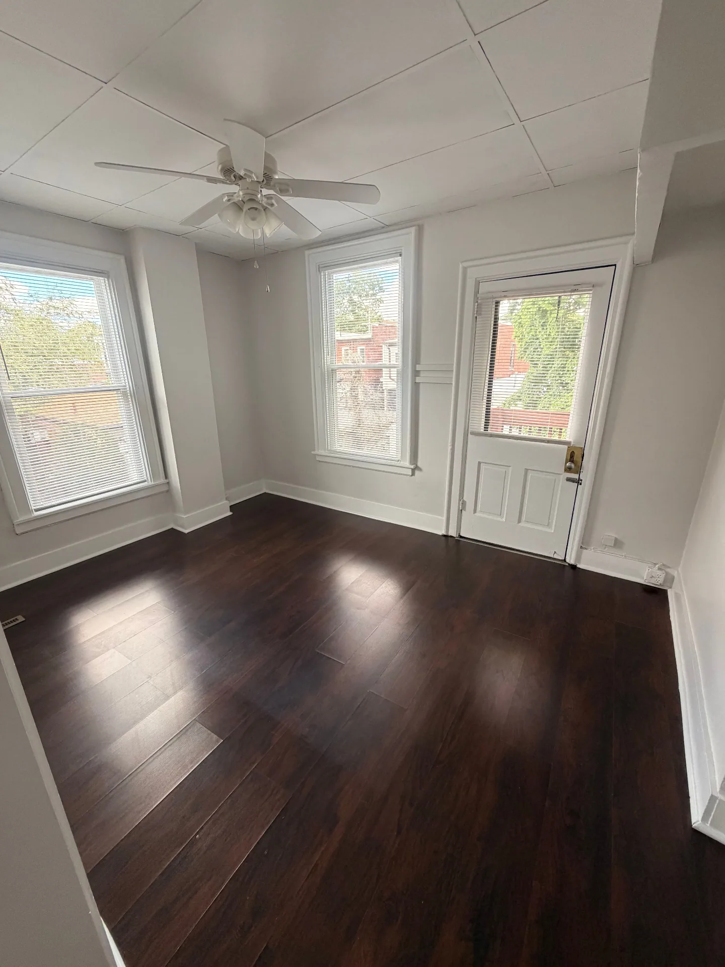 3340 Chestnut Upstairs bright living room with dark floors, three windows and a back door to the deck