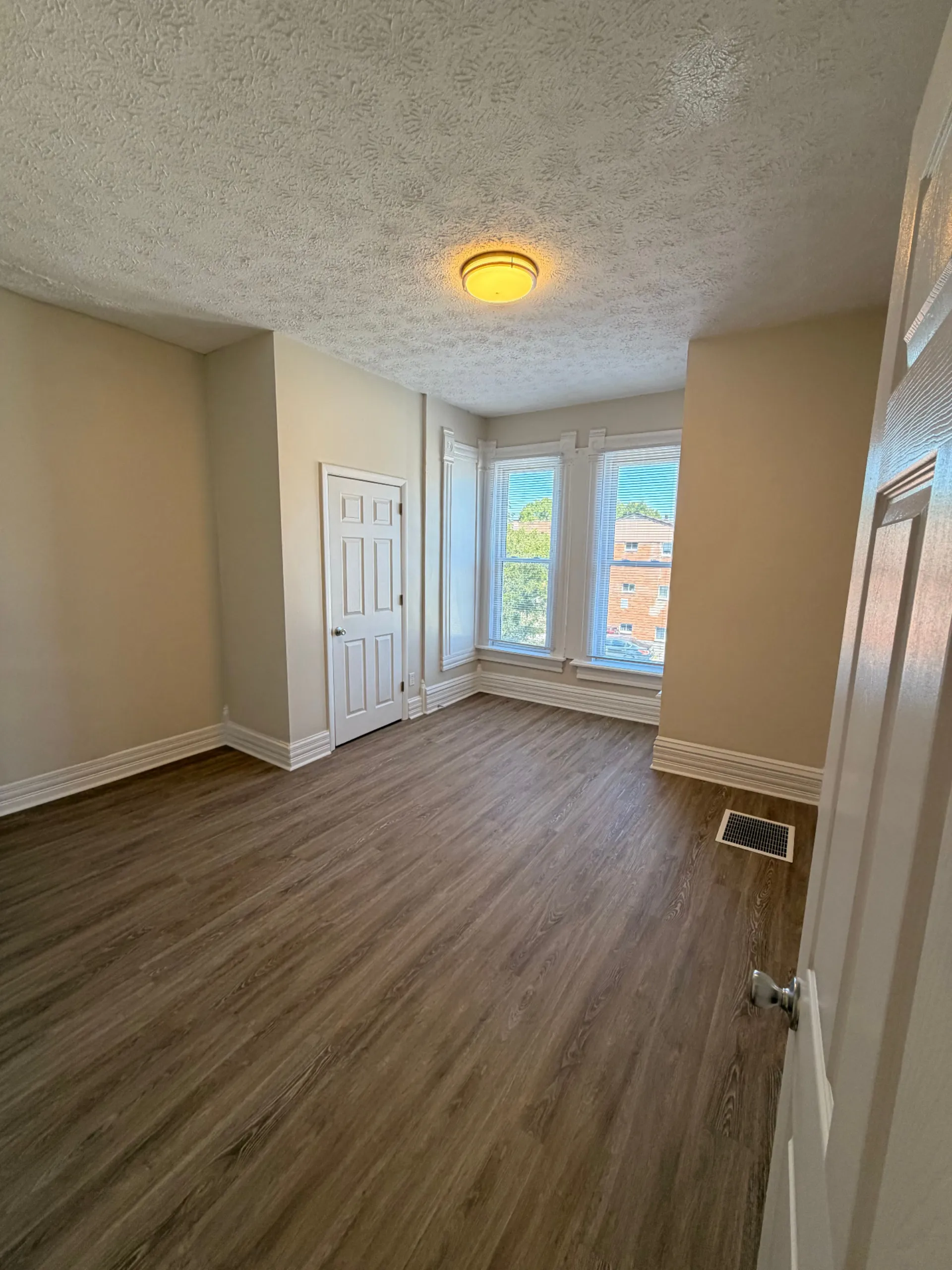 133½ bedroom with bay windows, plank flooring and high ceilings