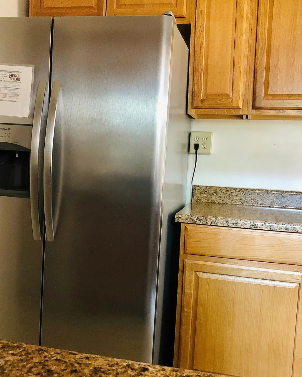 Unit A kitchen with stainless steel side-by-side refrigerator and wood cabinetry