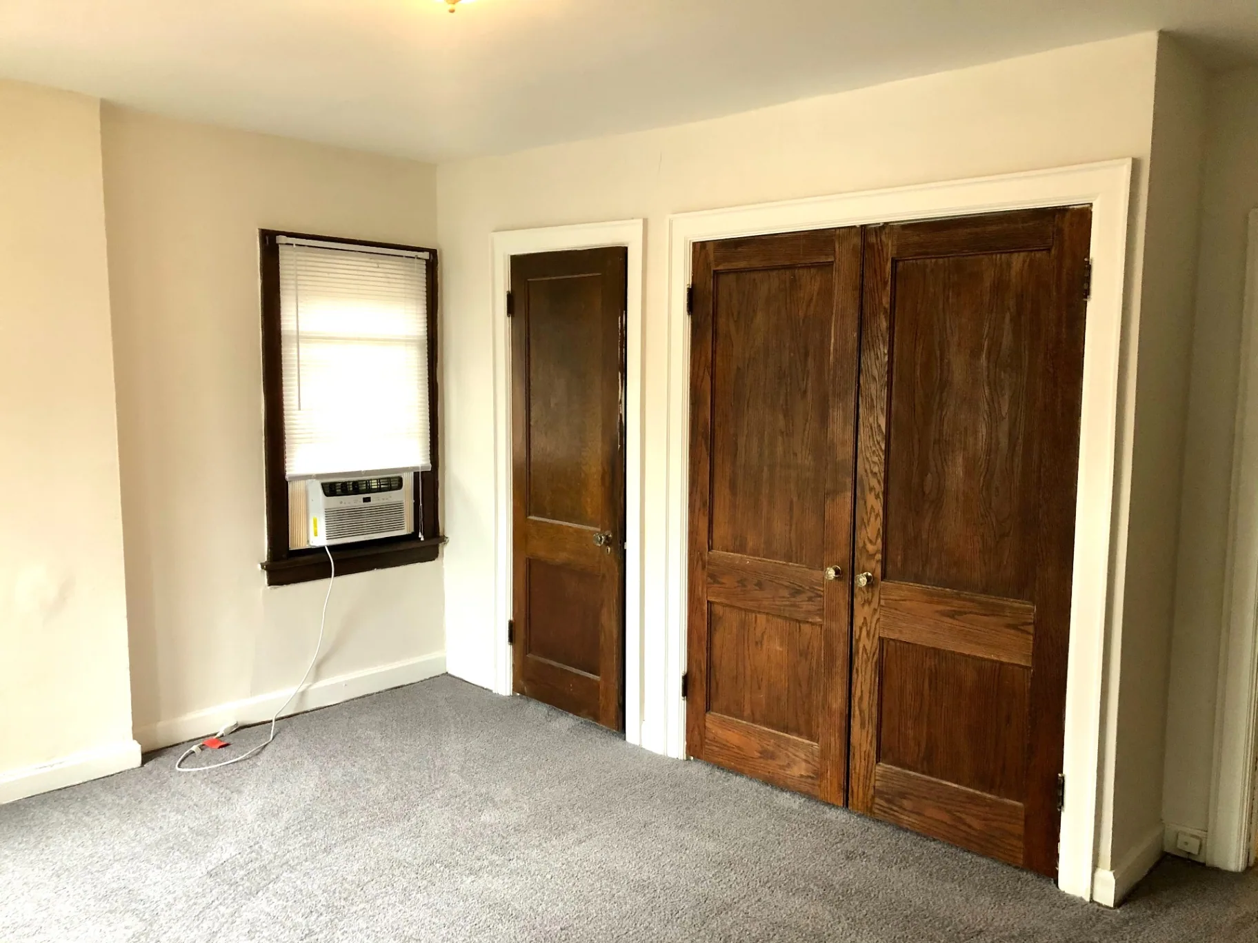 2044 Iuka Ave. B bedroom with large double wood closet doors and window AC