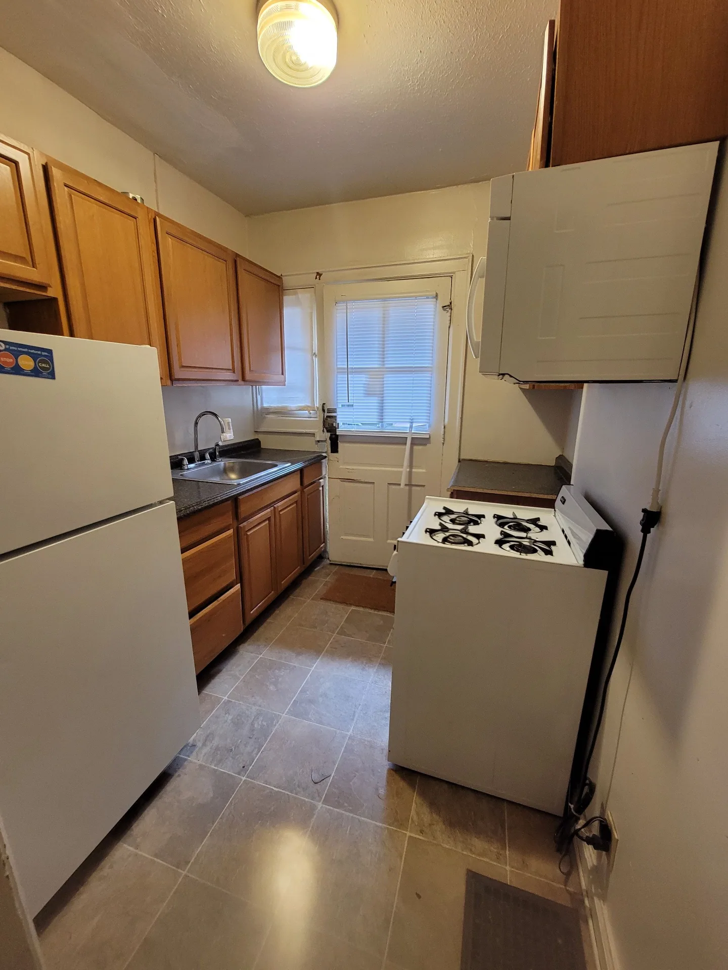 2048 Iuka Ave. B galley kitchen with gas range, full-size fridge, and rear door to exterior stairs