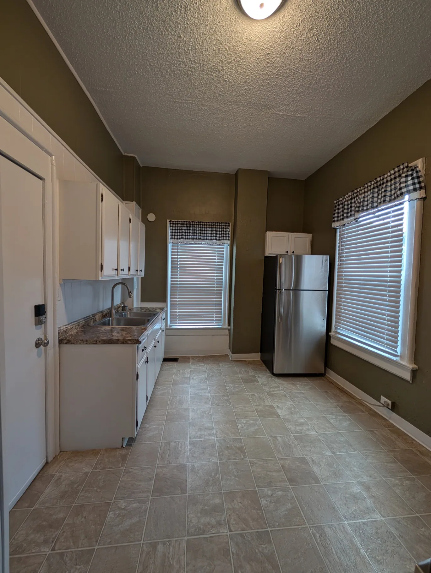 3338 Chestnut Downstairs eat-in kitchen with white cabinets, tile floor and stainless fridge