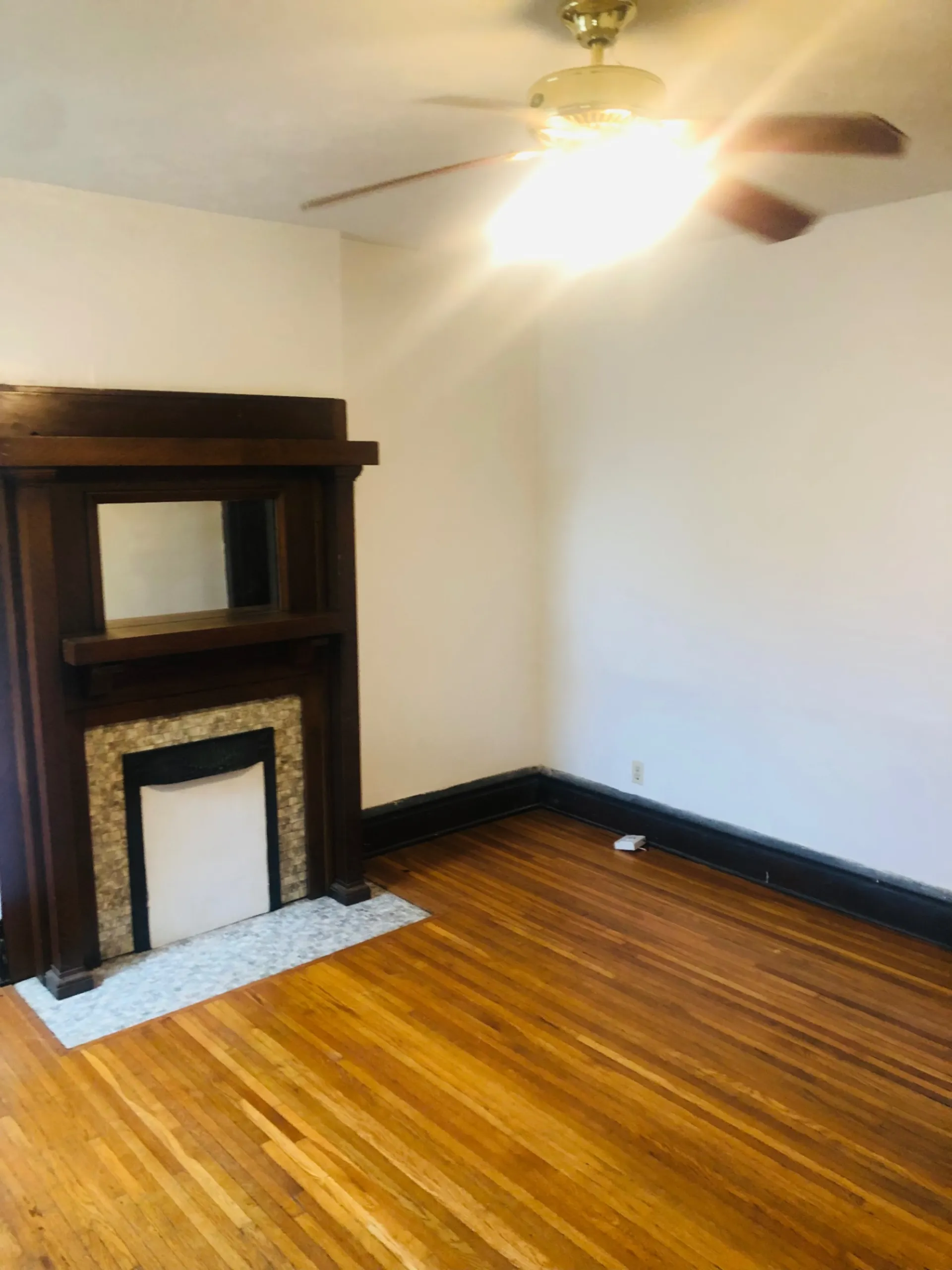 119 W 9th living room with original dark wood mantel and refinished hardwood floors