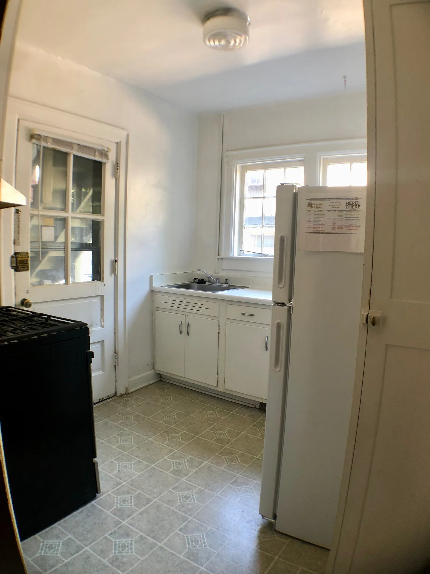 2044 Iuka Ave. A kitchen with rear entry door, full-size refrigerator, and bright double windows above the sink