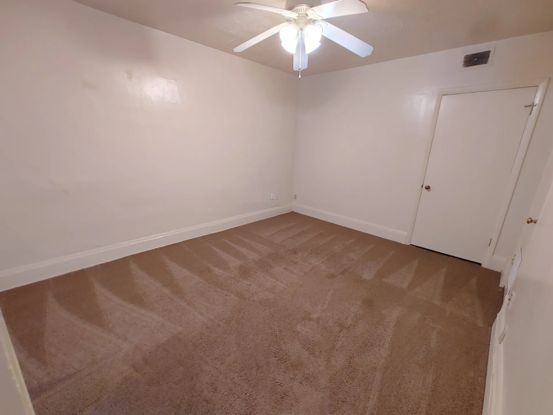 Rear unit main-floor bedroom with ceiling fan and fresh carpet