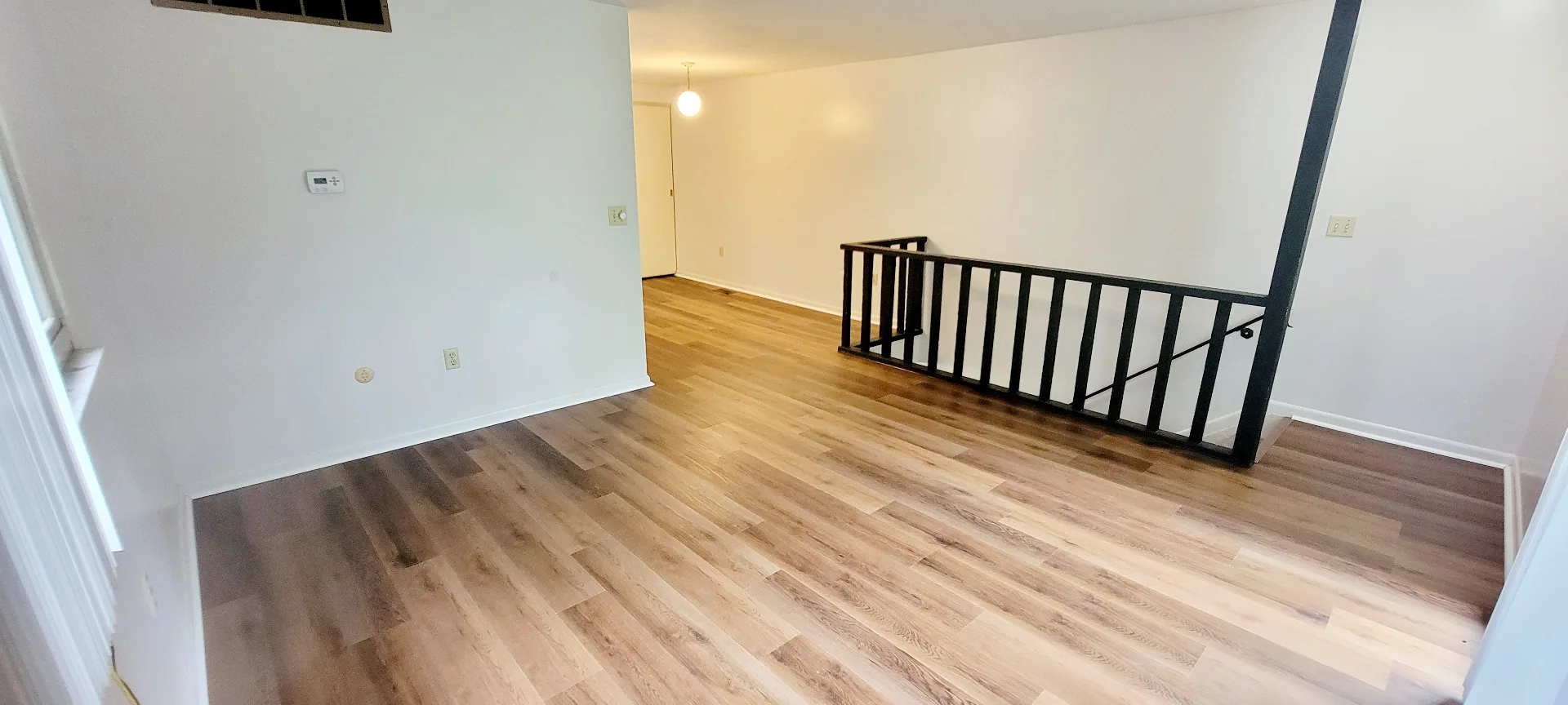 2022 Summit St. wide open living area with plank flooring, black stair railing, and bright walls