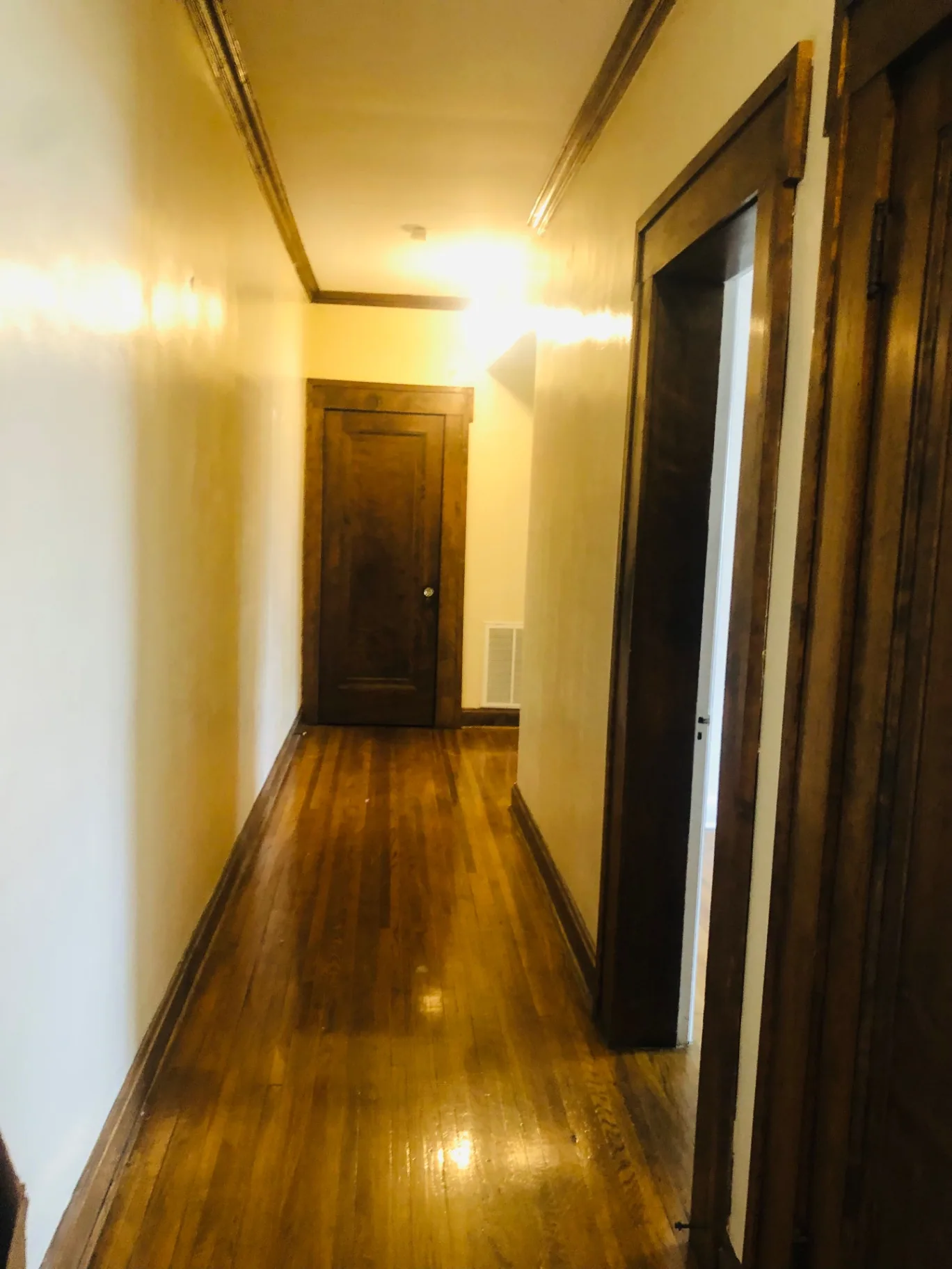 Unit K hallway with hardwood floors and dark wood doors and trim
