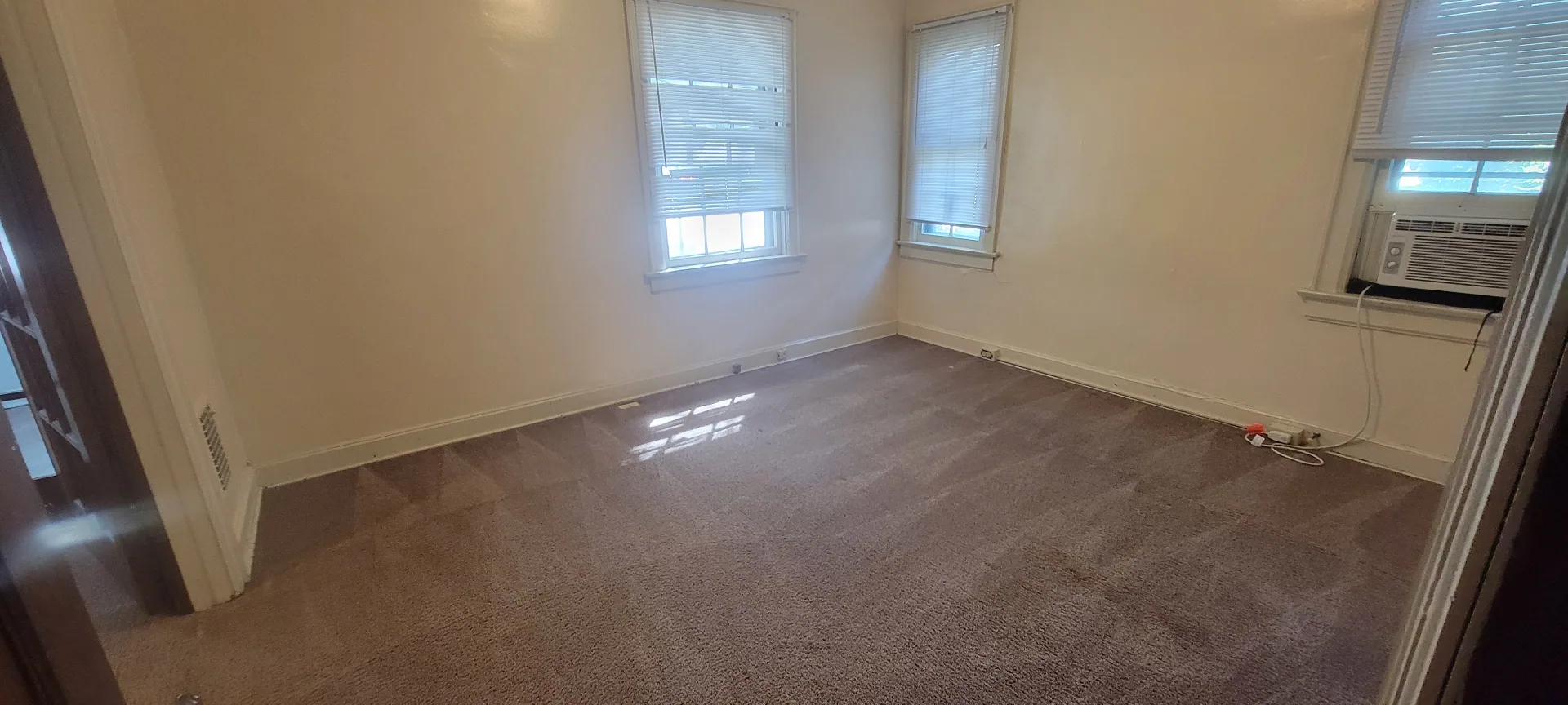 2054 Iuka Ave. A bedroom with three windows, window AC, and fresh carpet