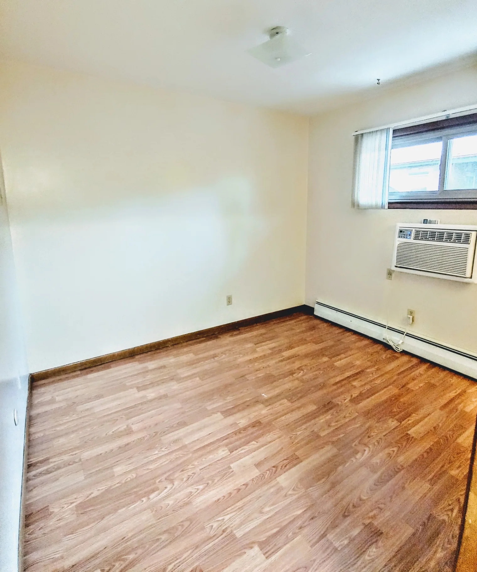 2040 Iuka Ave. 1B bedroom with wood laminate floors, large window, and AC unit