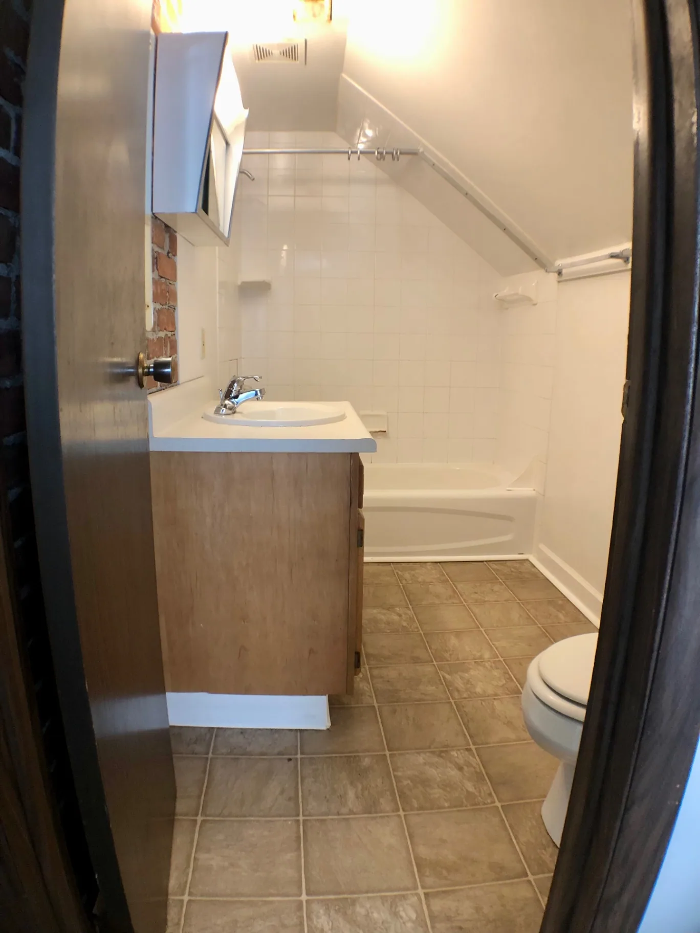 Full bathroom with tub, tile surround, vanity, and sloped attic ceiling