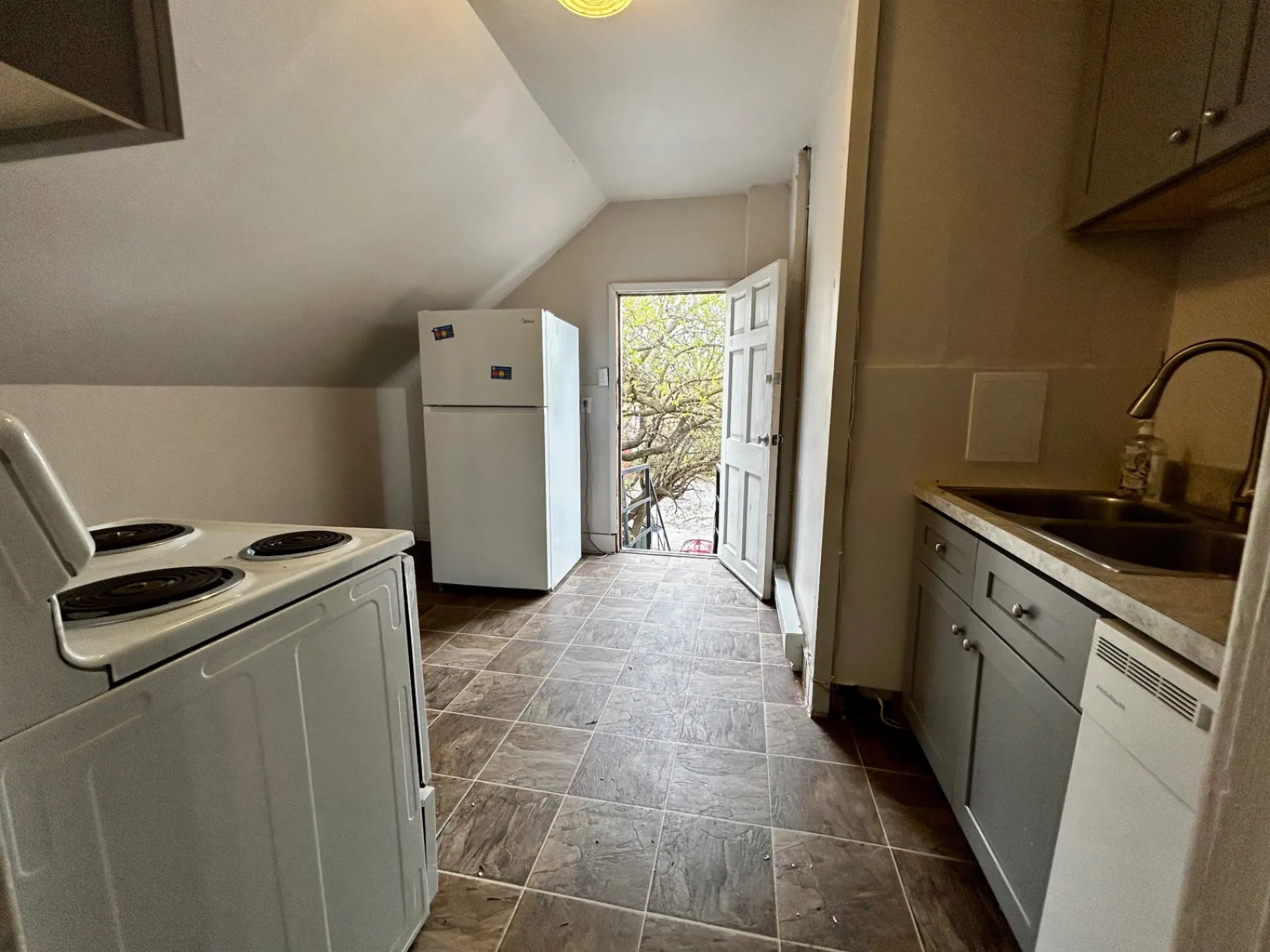 1820 Summit St. kitchen with full-size fridge and open rear door bringing in natural light