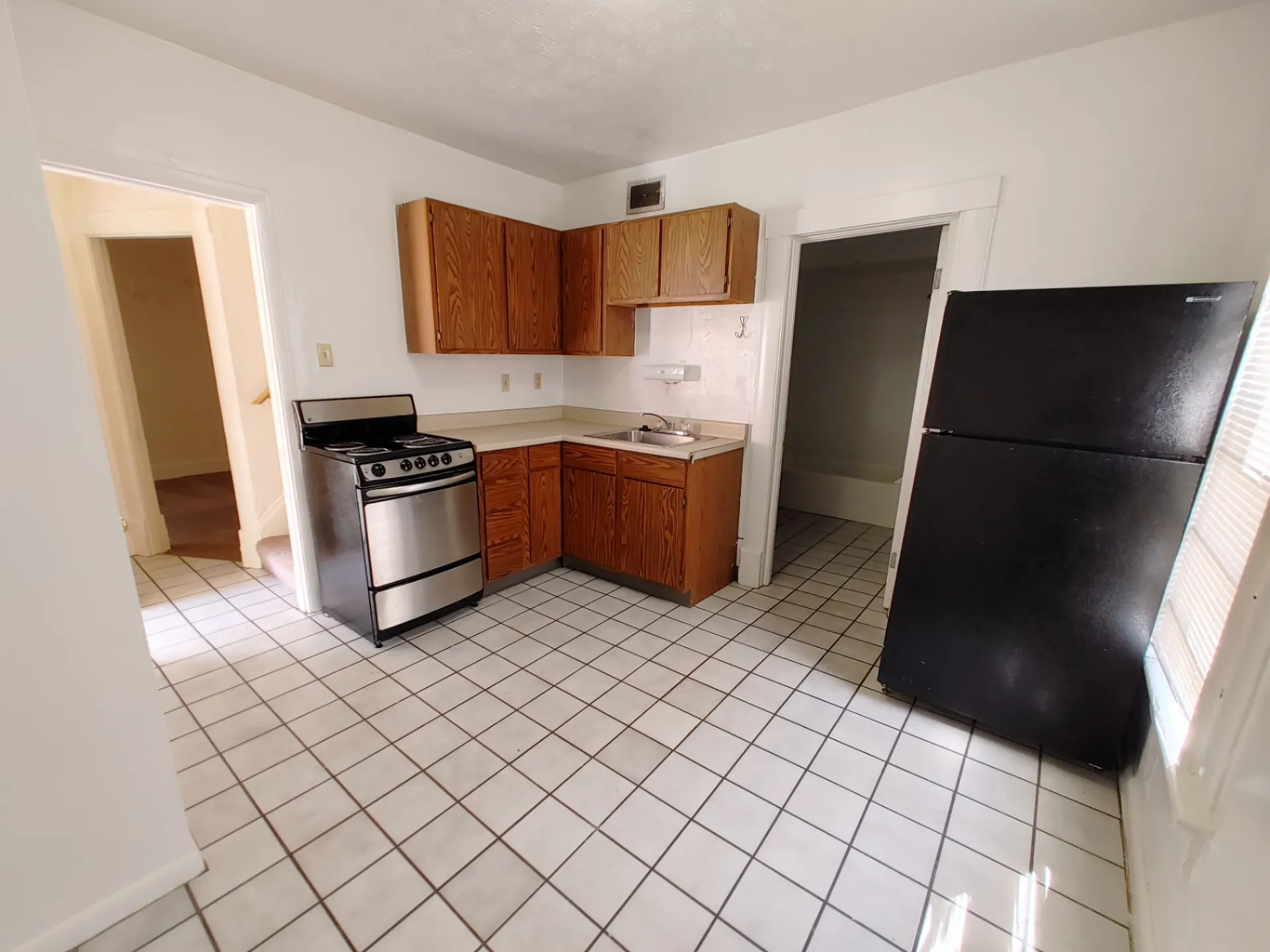 Rear unit bright eat-in kitchen with tile floor, stainless-front range, full-size fridge and updated cabinets